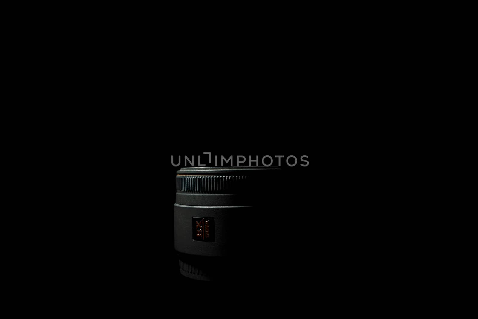 Ukraine; Kyiv; 20.02.2019 Sigma 50mm f1:2,8 DG EX Macro lens. Underexposed photo of DSLR camera lens lying on black background. Stock photo isolated. Low light photo and large depth of field.