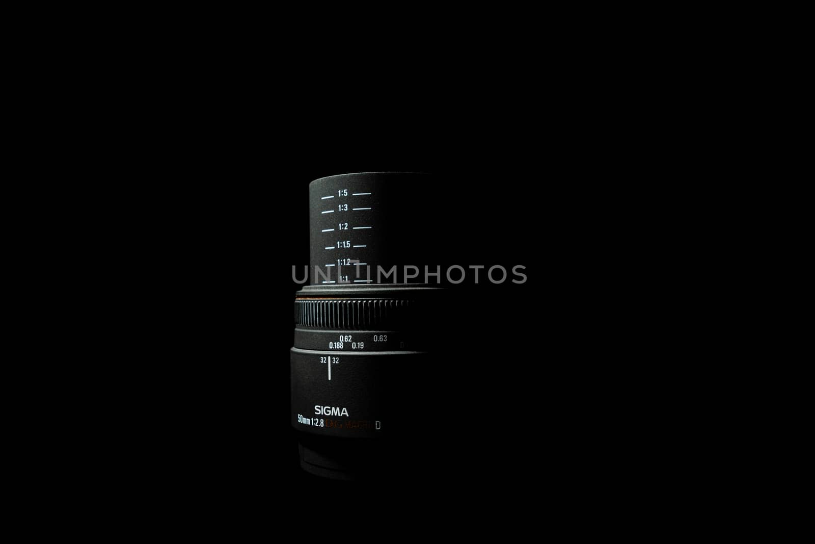 Ukraine; Kyiv; 20.02.2019 Sigma 50mm f1:2,8 DG EX Macro lens. Underexposed photo of DSLR camera lens lying on black background. Stock photo isolated. Low light photo and large depth of field.