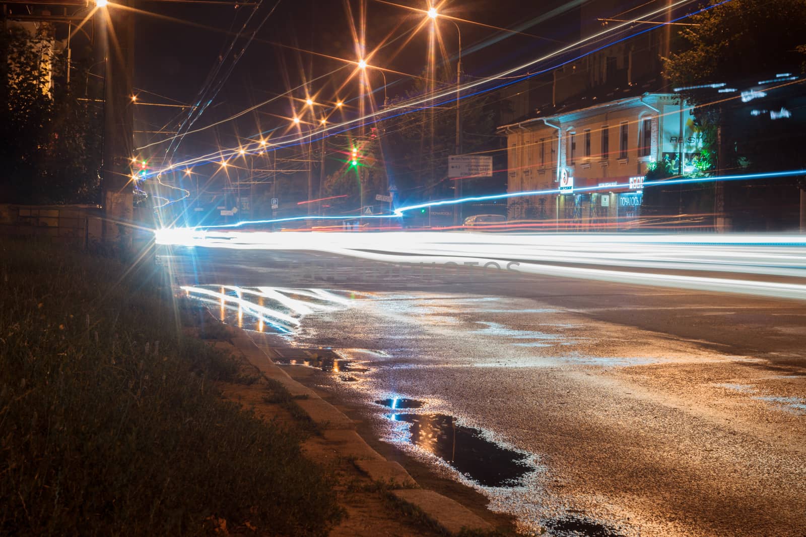 Long exposure vehicle lights in city. Uneven light lines and reflection in a puddle. Editorial use only.