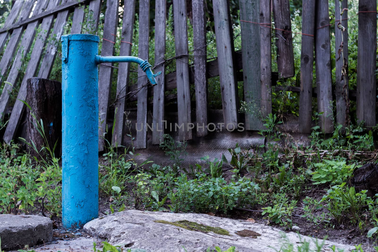 The blue broken water hydrant. Paint is very old and cracked.