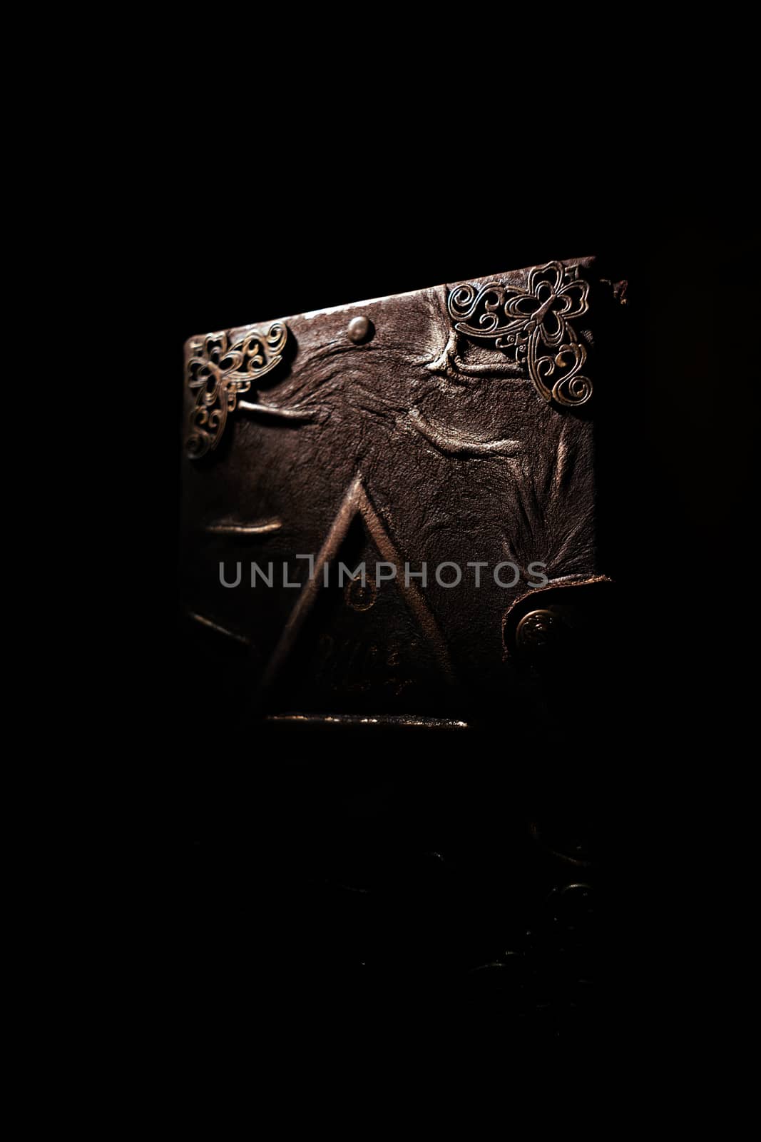 Low light handmade old leather cover notebook. Charred sheets and cover isolated on black background. Underexposed stock photo.