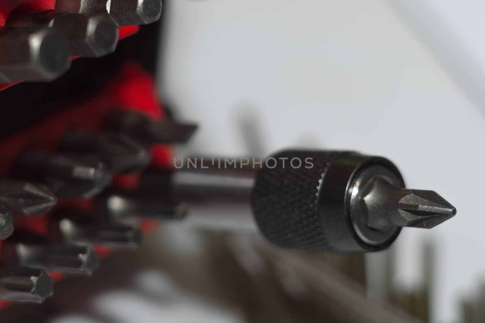 Bits holder in box and many tool bits on white background. Close-up view. Red element in plastic box.