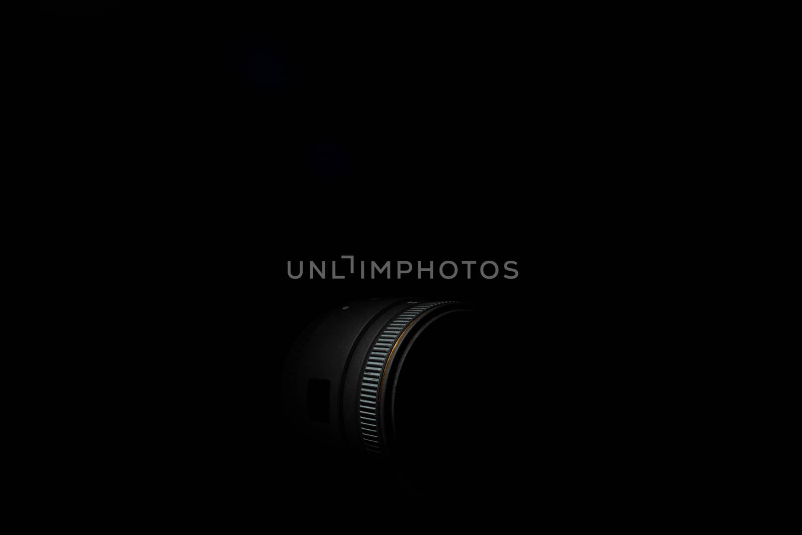 Underexposed photo of DSLR camera lens. Stock photo isolated on black background. Low light photo and large depth of field.