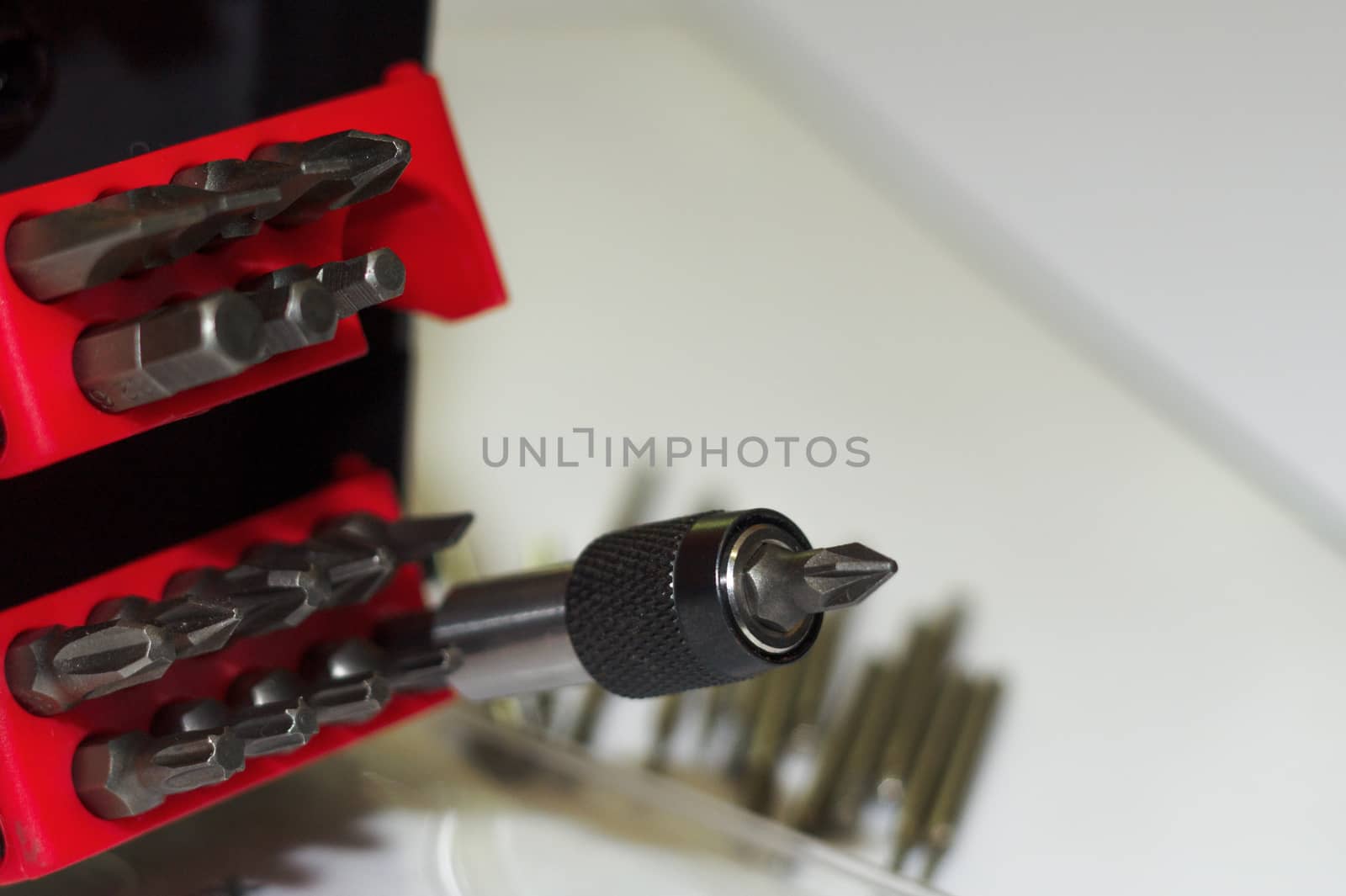 Bits holder in box and many tool bits on white background. Close-up view. Red element in plastic box.