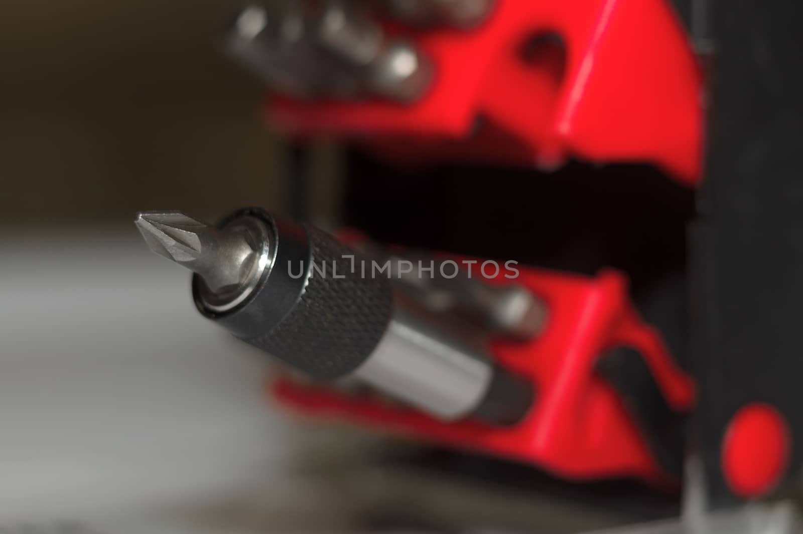 Bits holder in box and many tool bits on white background. Close-up view. Red element in plastic box.