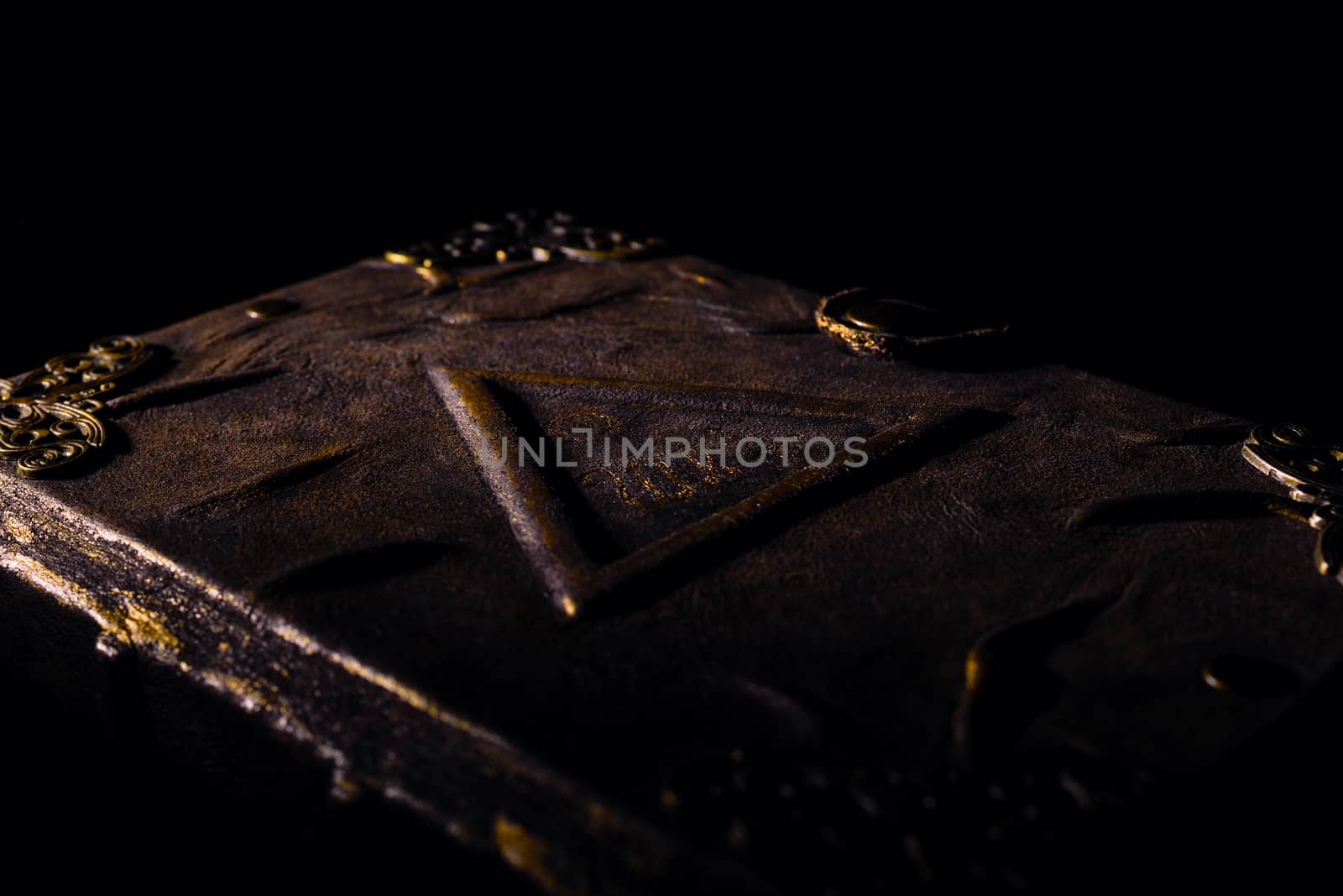 Low light old handmade leather cover notebook. Old leather cover isolated on black background. Underexposed stock photo.