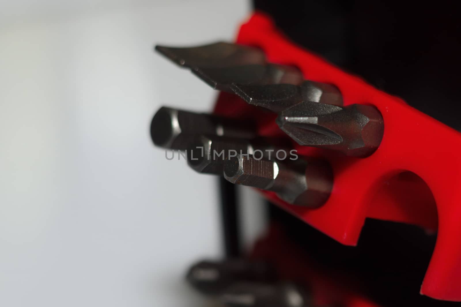 Bits holder in box and many tool bits on white background. Close-up view. Red element in plastic box.
