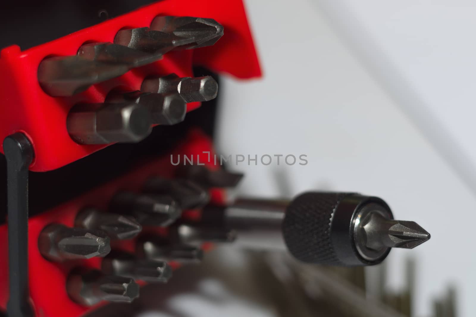 Bits holder in box and many tool bits on white background. Close-up view. Red element in plastic box.