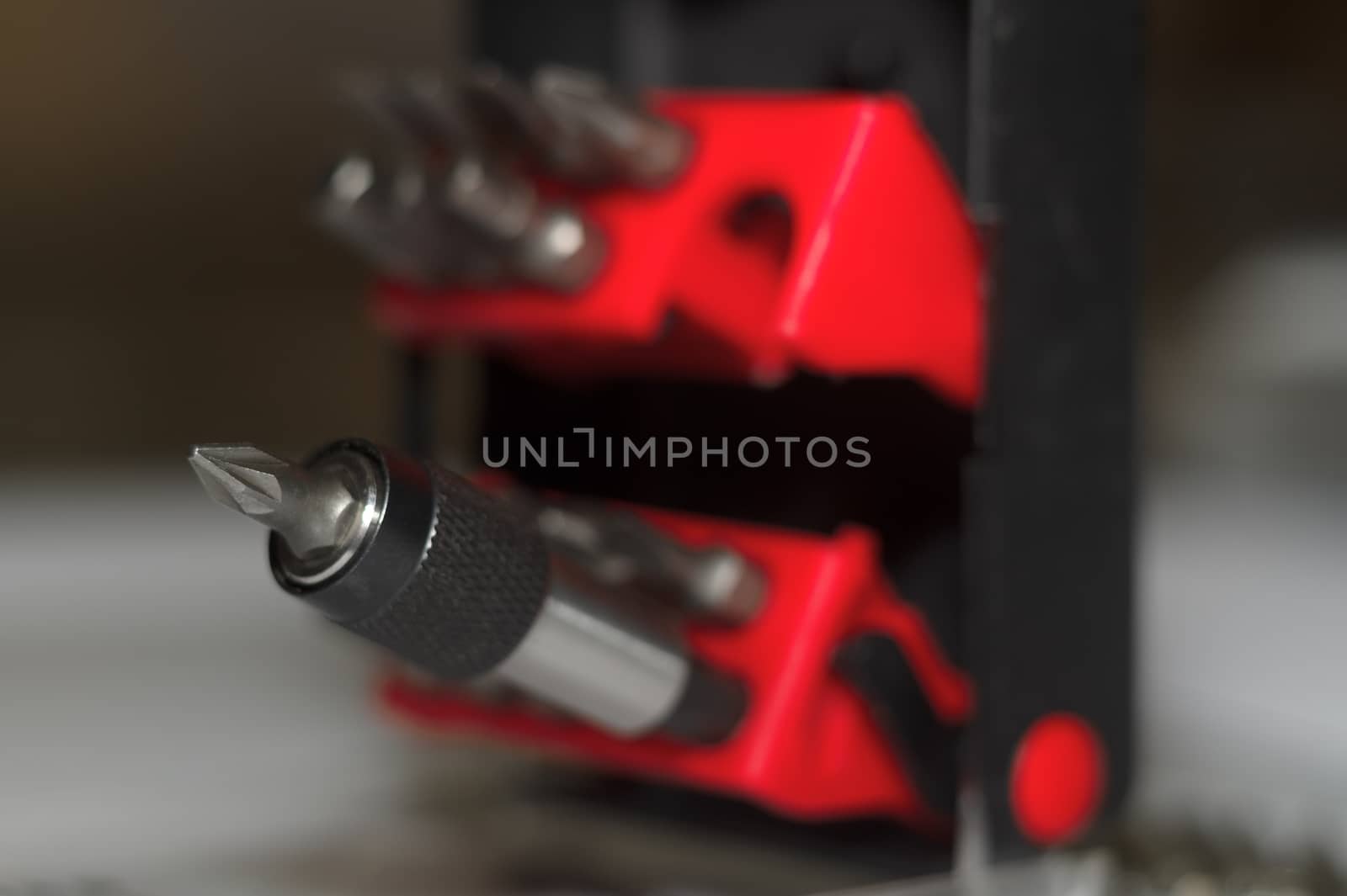Bits holder in box and many tool bits on white background. Close-up view. Red element in plastic box.