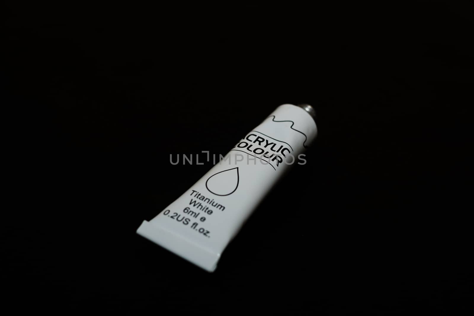 Acrylic white titanium paint metal tube on black background. New tube. Aluminium tube of paint.