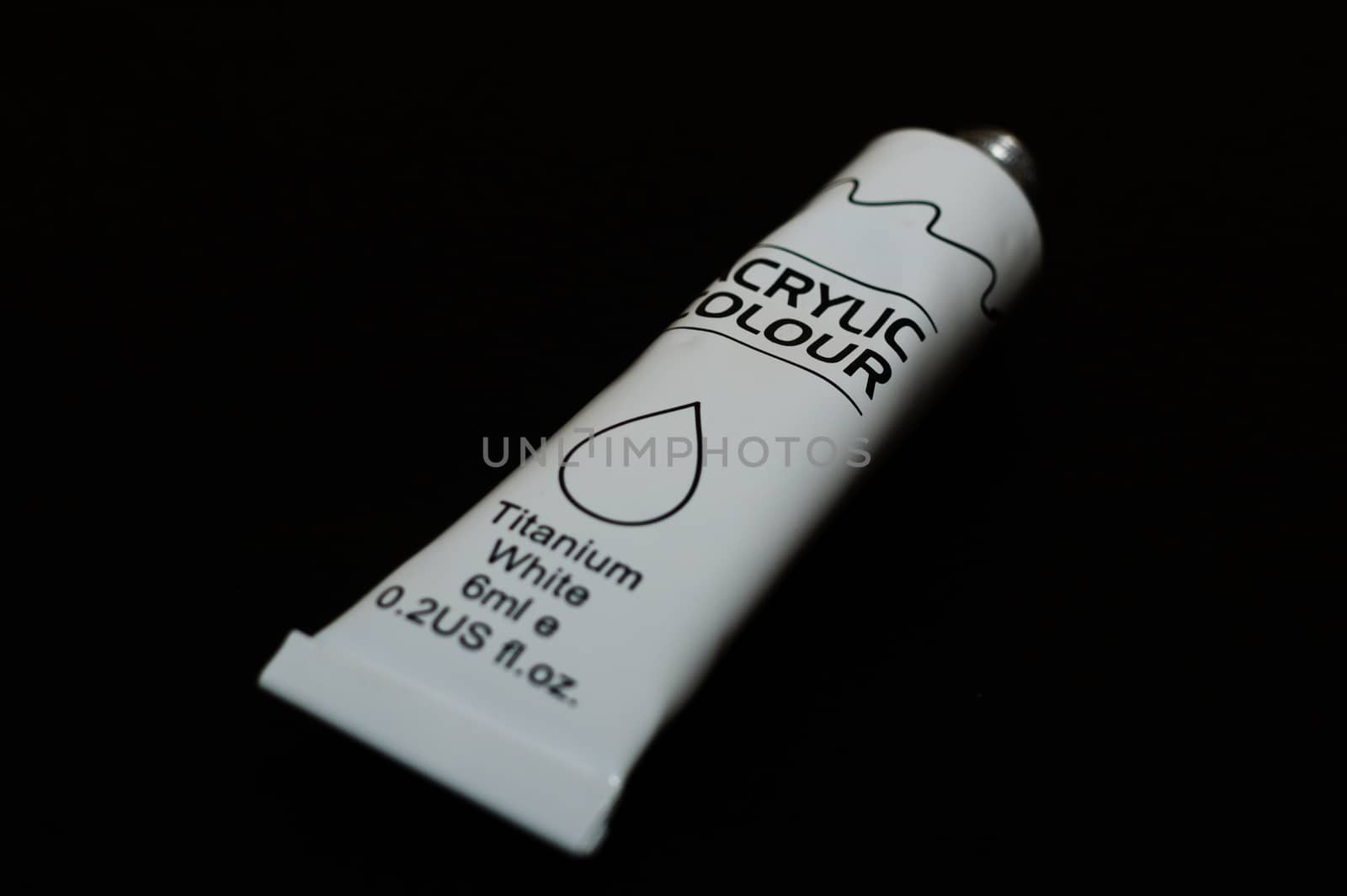 Acrylic white titanium paint metal tube on black background. New tube. Aluminium tube of paint.