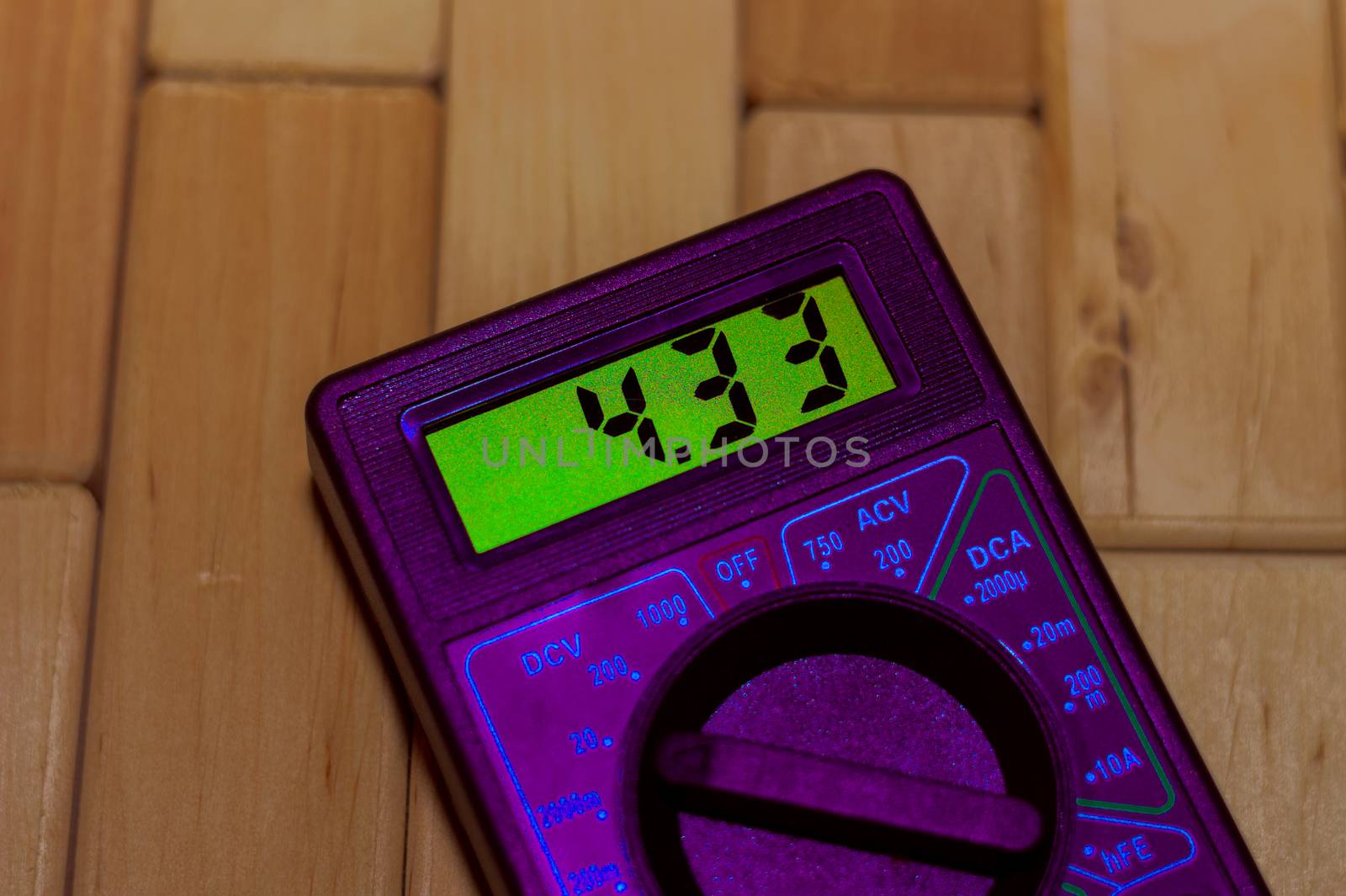 Purple digital measuring multimeter on wooden floor. It shows 4.33V on green screen or fully charged battery. Includes voltmeter, ampermeter, ohmmeter.
