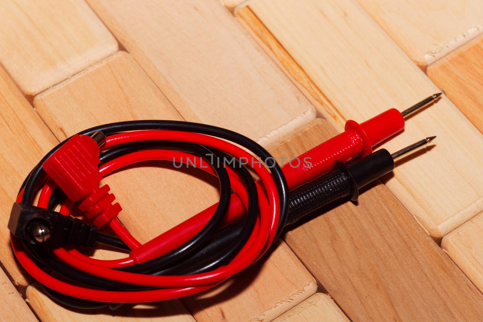 probes of a digital multimeter on the floor of wooden planks