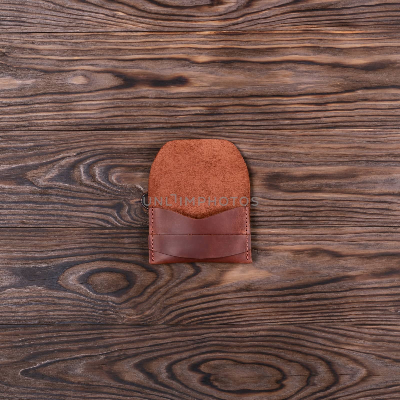 Flat lay photo of ginger colour handmade leather one pocket cardholder. Stock photo on wooden background.
