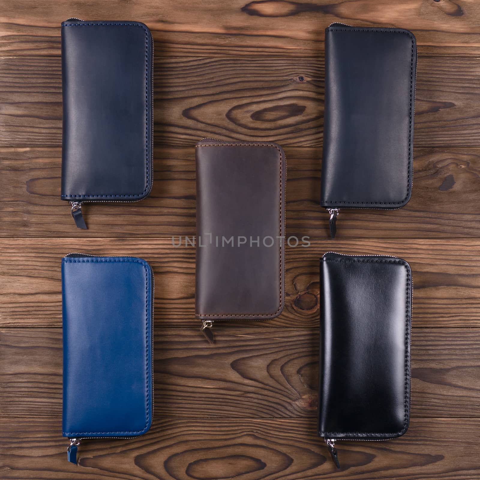 Five handmade leather porte-monnaie on wooden textured background.  Up to down view. Stock photo of luxury accessories.