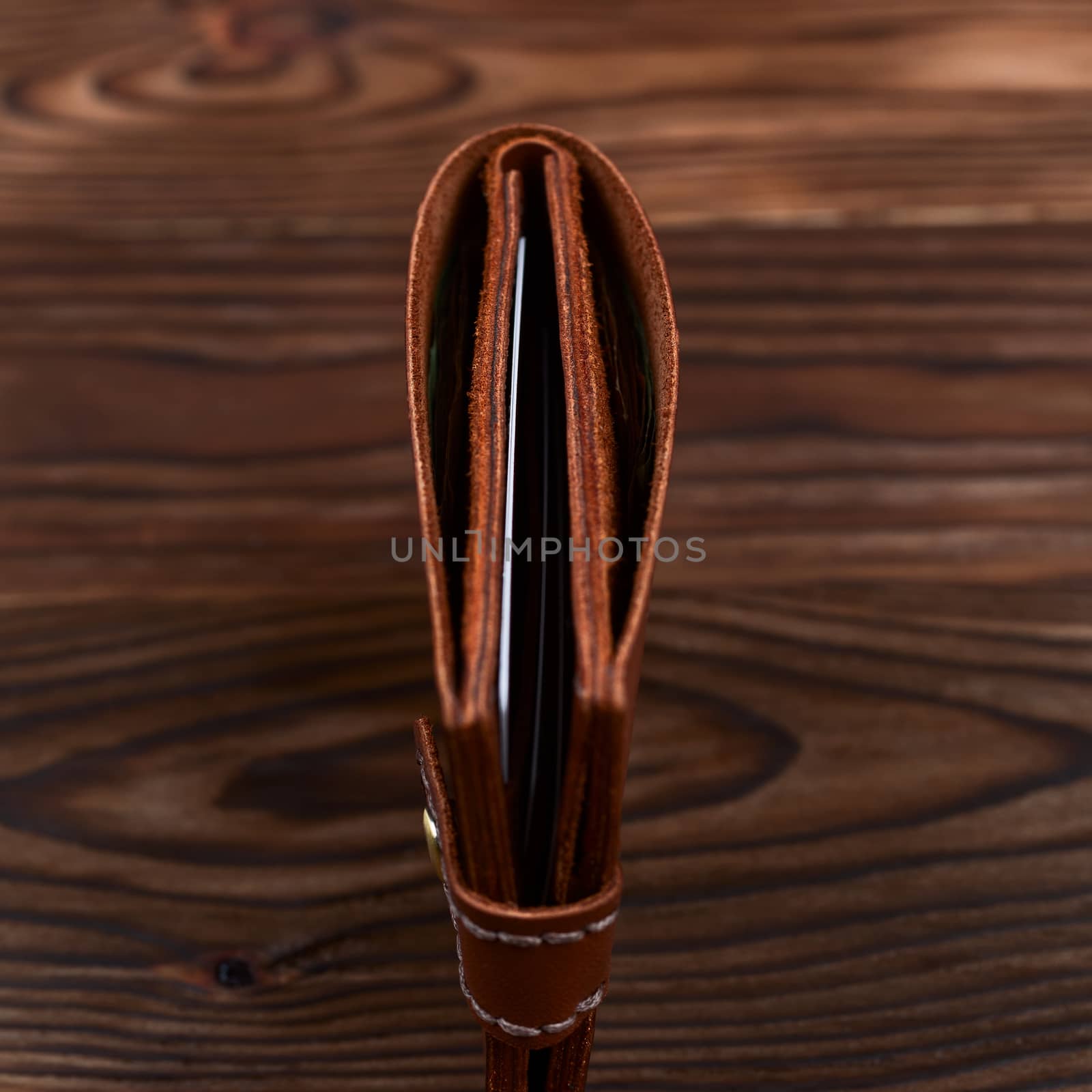 Handmade leather gloss wallet on wooden textured background. Businessman wallet stock photo.