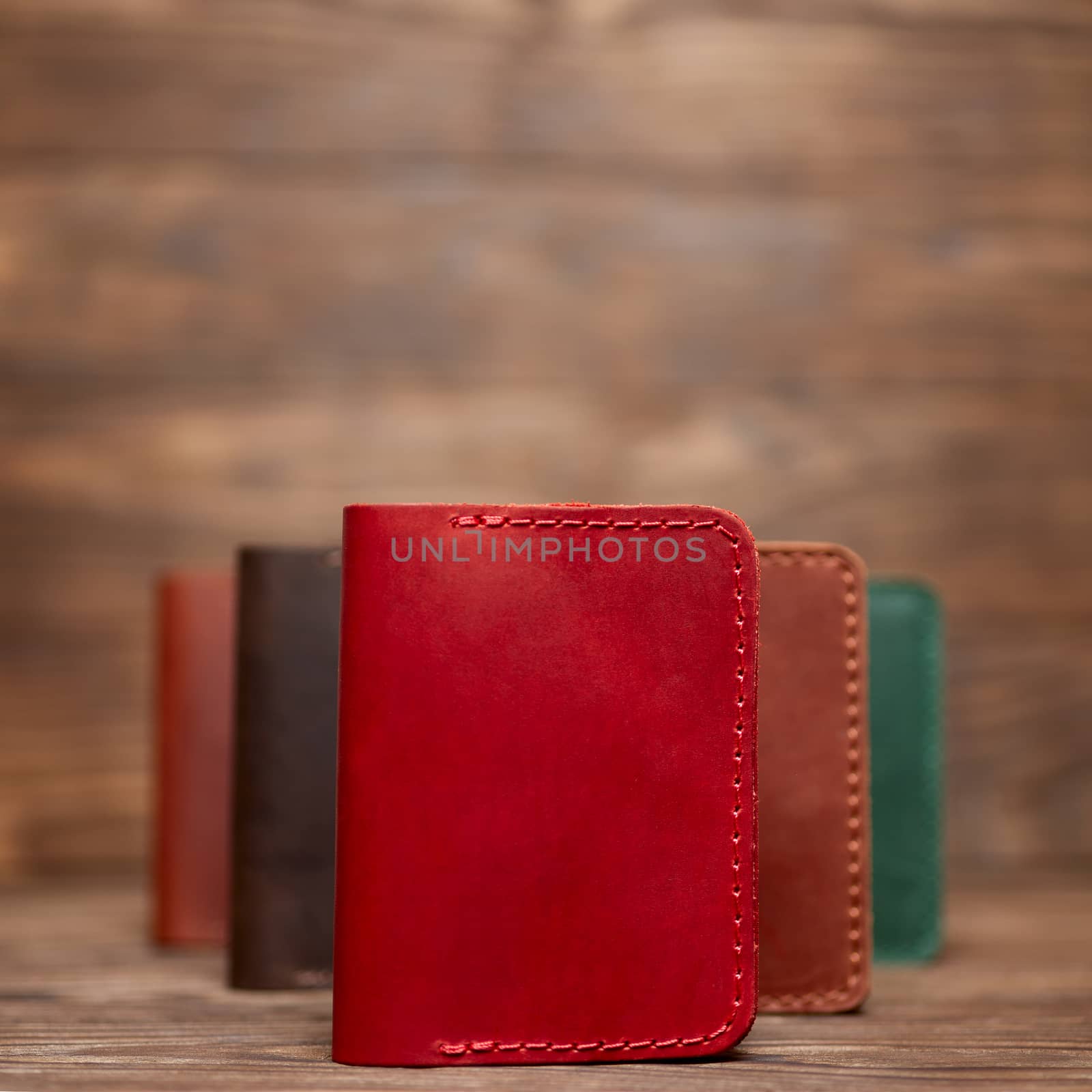 Soft focus photo of red colour handmade leather cardholder. Blurred background on photo. Different colour cardholders blurred on background.
