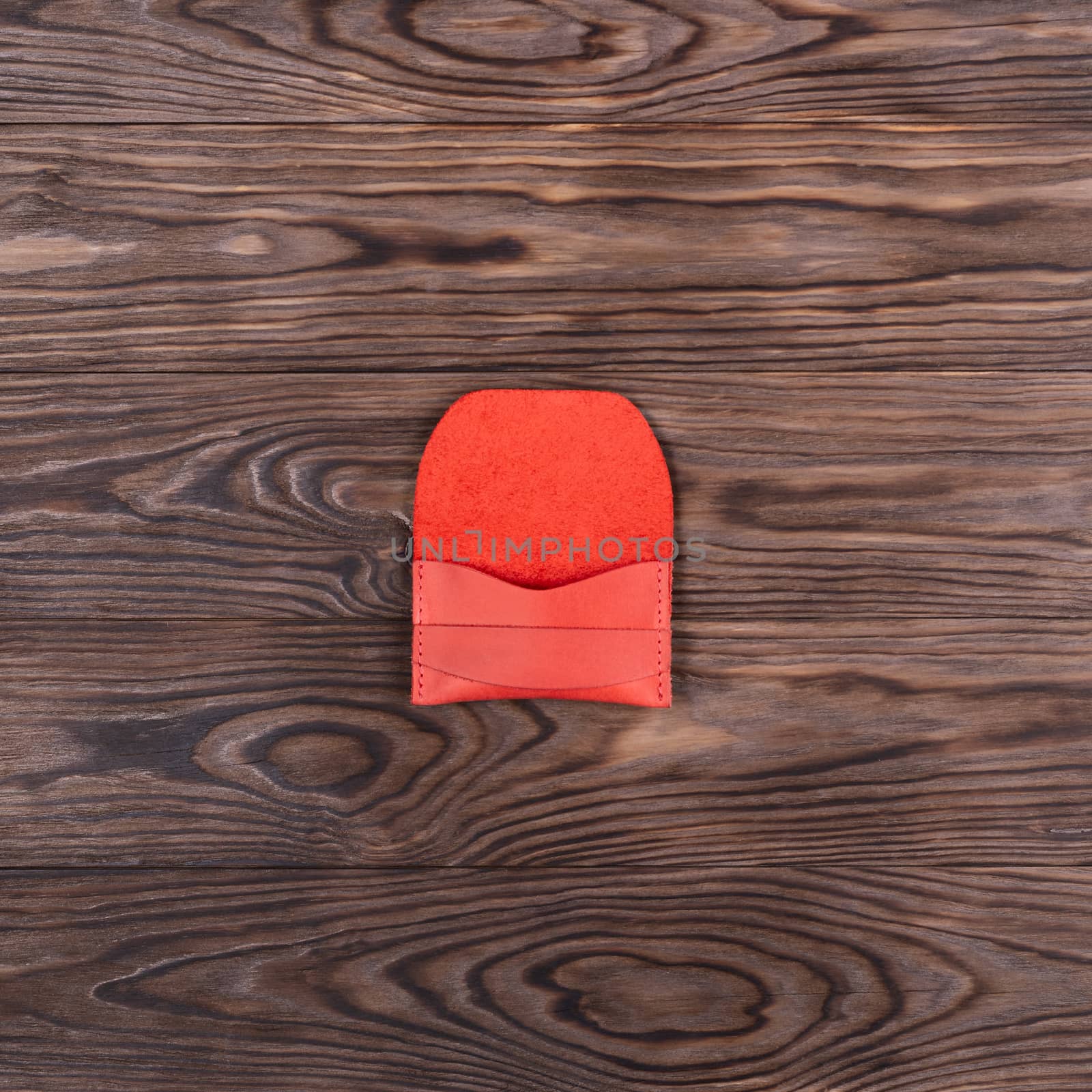 Flat lay photo of red colour handmade leather one pocket cardholder. Stock photo on wooden background.