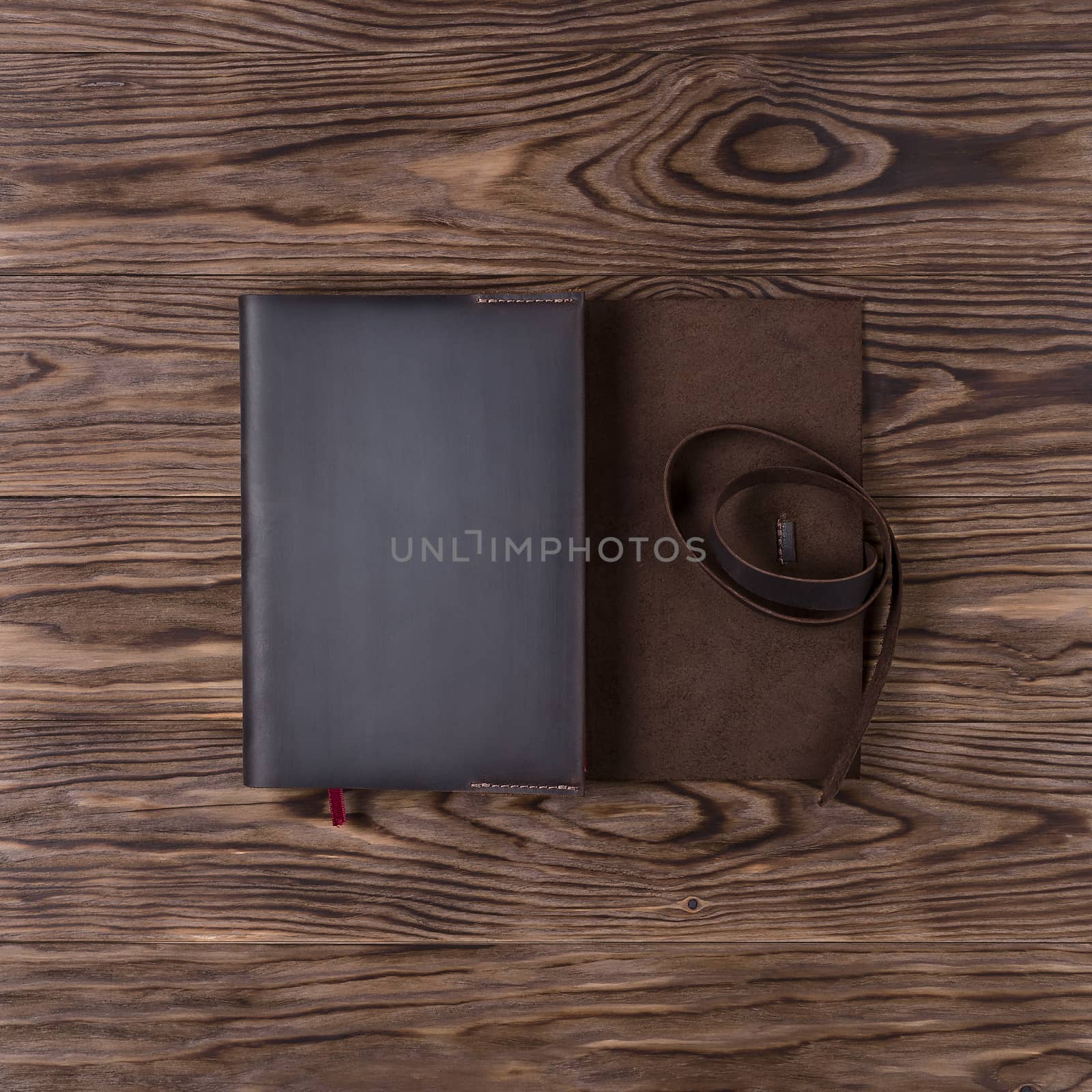 Brown handmade leather notebook cover with notebook on wooden background. Stock photo of luxury business accessories. Up to down view.