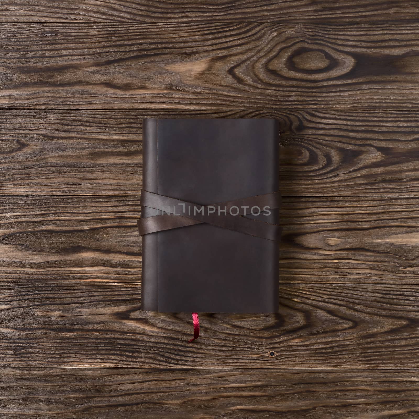 Brown handmade leather notebook cover with notebook on wooden background. Stock photo of luxury business accessories. Up to down view.