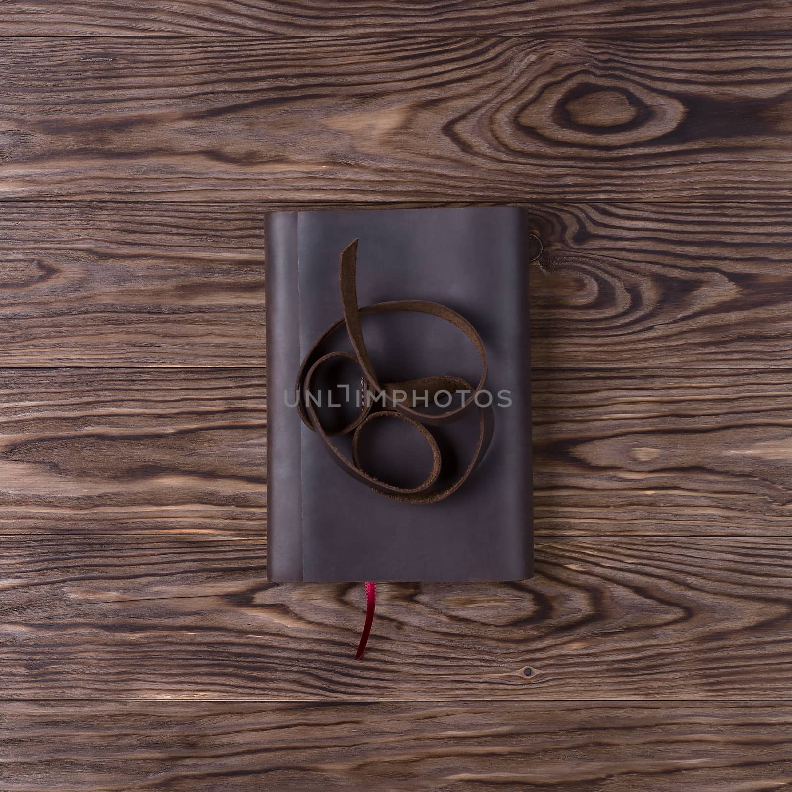 Brown handmade leather notebook cover with notebook on wooden background. Stock photo of luxury business accessories. Up to down view.