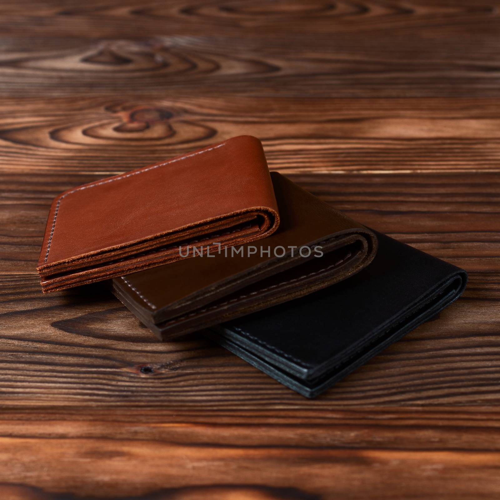 Three handmade leather wallets on wooden textured background. closeup. Wallet stock photo.