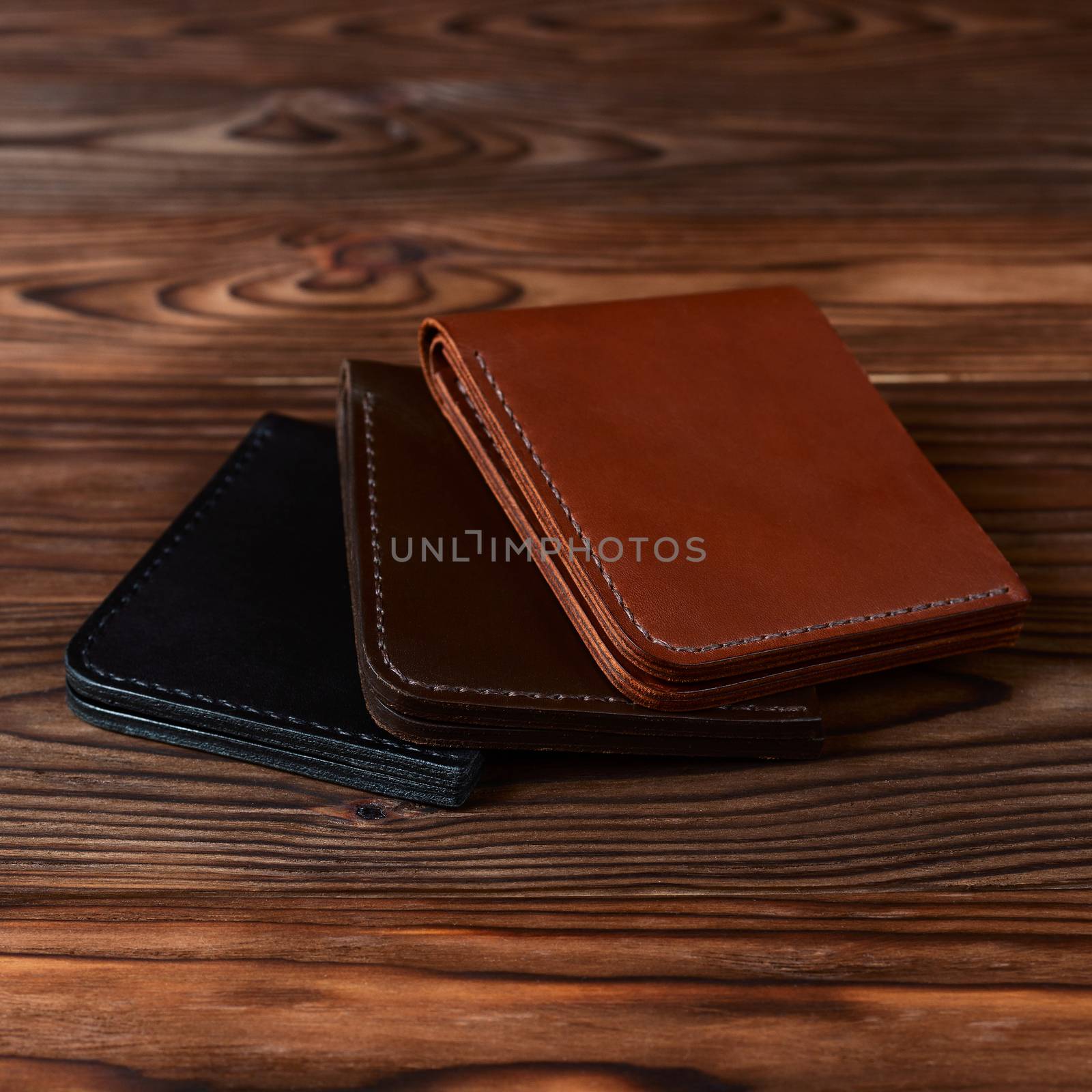 Three handmade leather wallets on wooden textured background. closeup. Wallet stock photo.