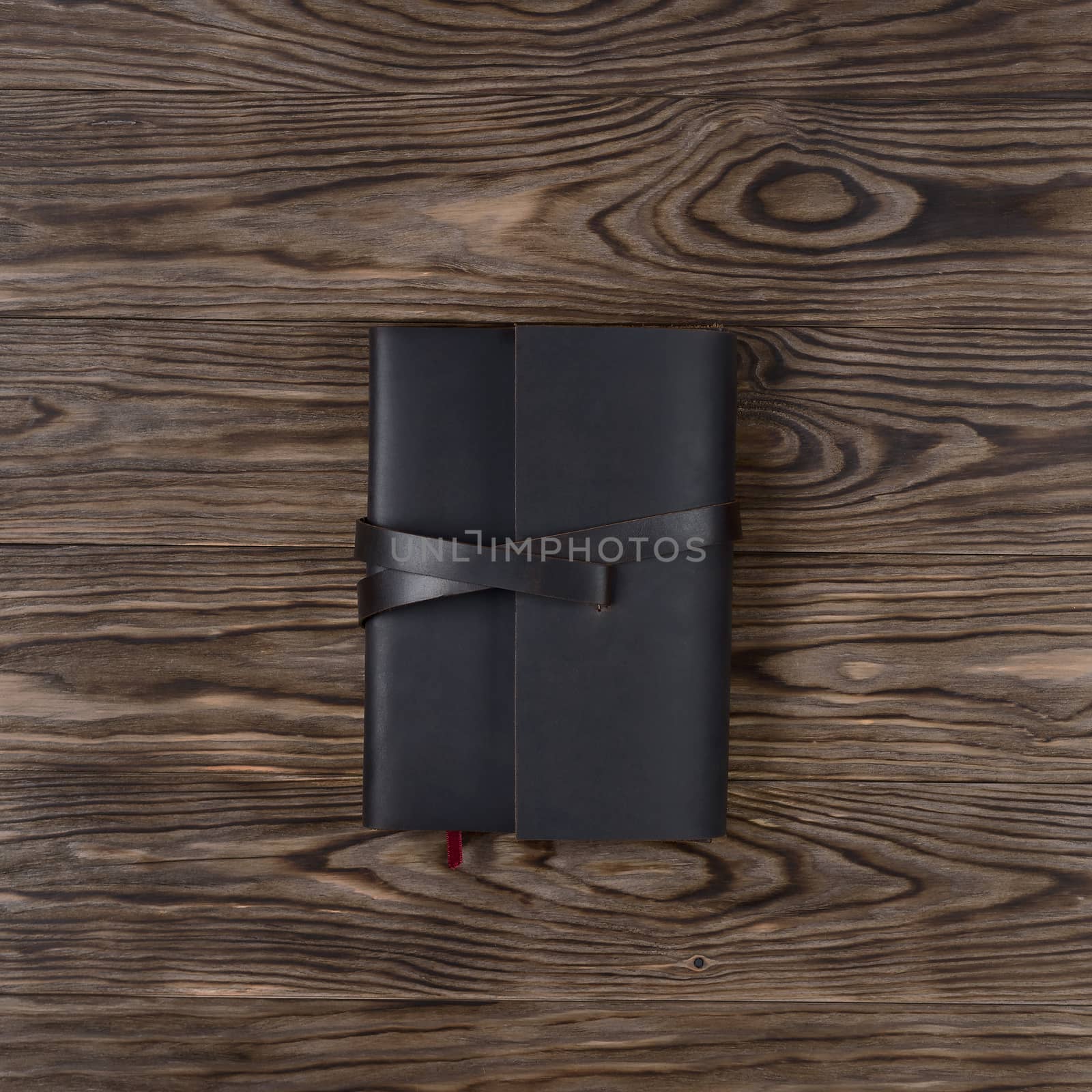 Dark brown handmade leather notebook cover with notebook on wooden background. Stock photo of luxury business accessories. Up to down view.