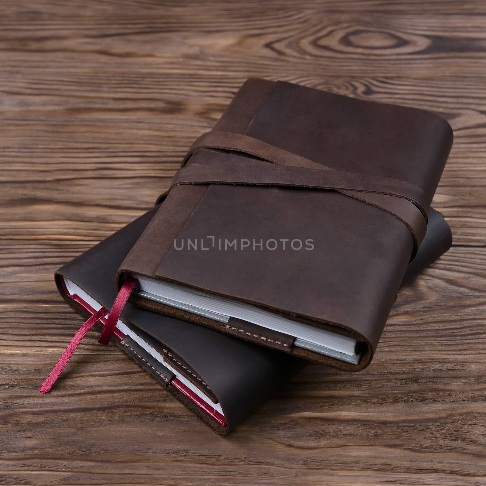 Brown and black handmade leather notebook cover with notebook inside on wooden background. Stock photo of luxury business accessories.