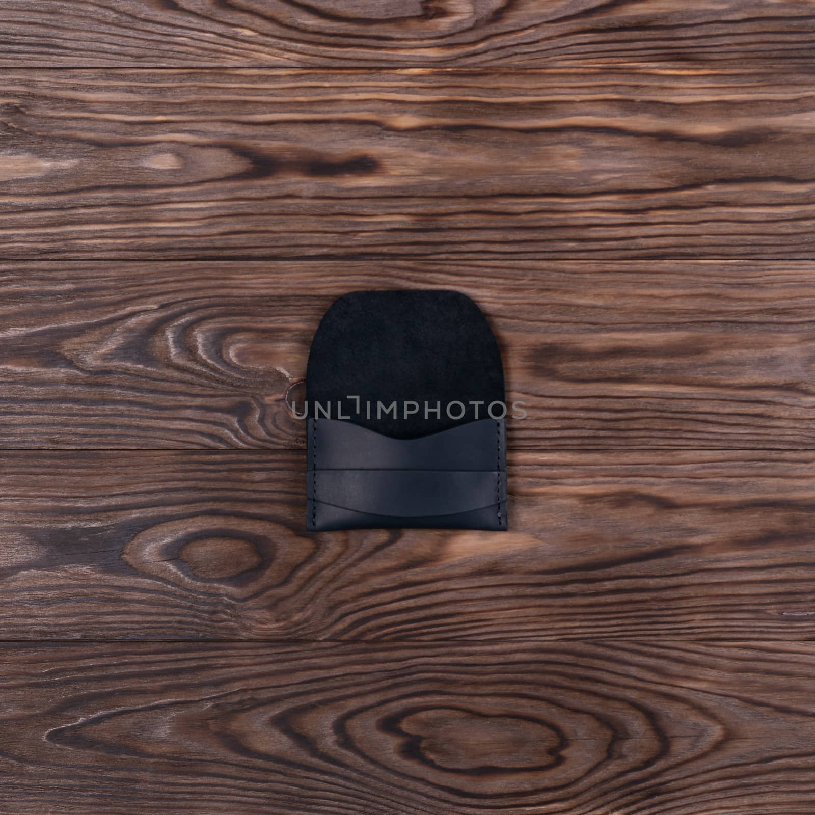 Flat lay photo of black colour handmade leather one pocket cardholder. Stock photo on wooden background.
