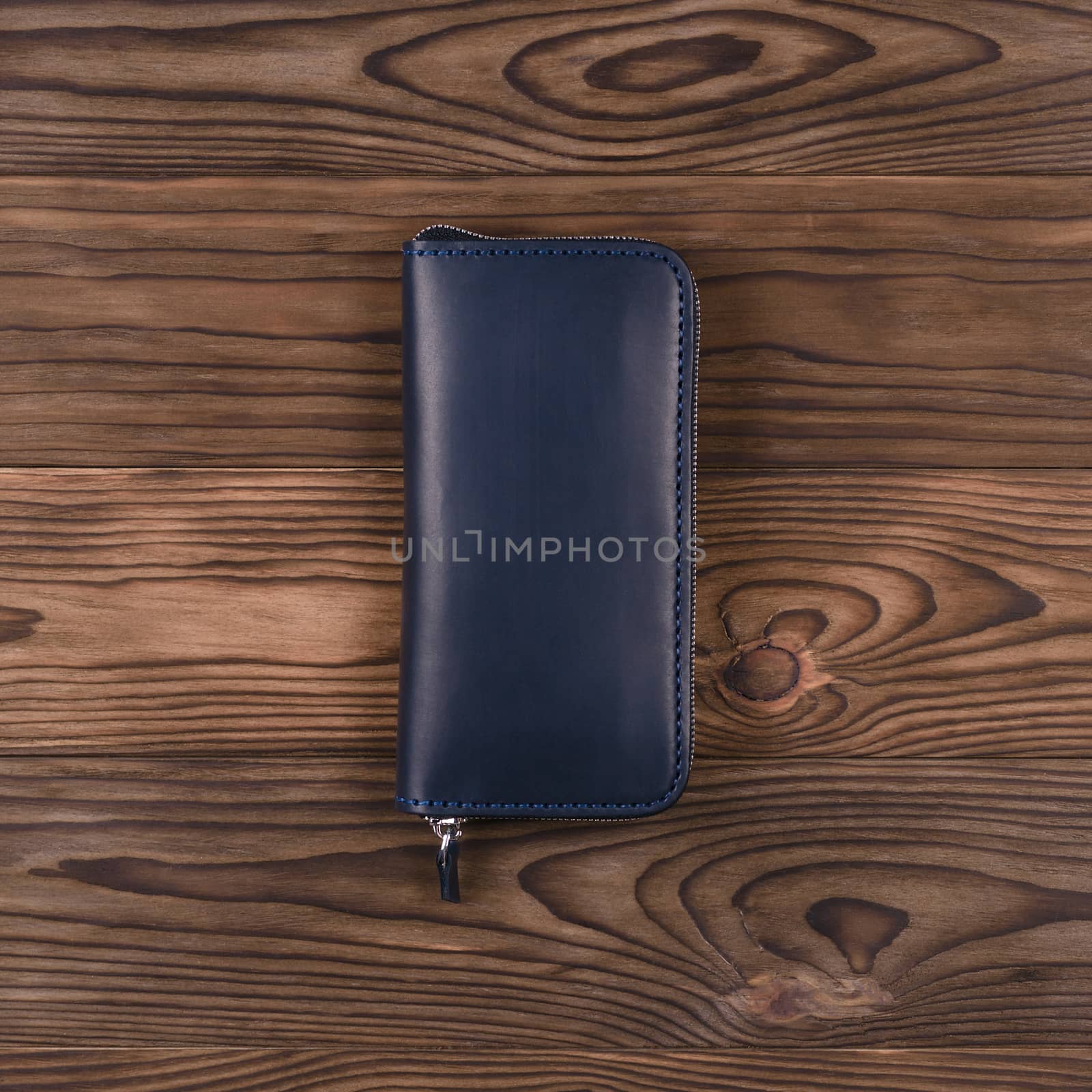Dark blue color handmade leather porte-monnaie on wooden textured background.  Up to down view. Stock photo of luxury accessories.