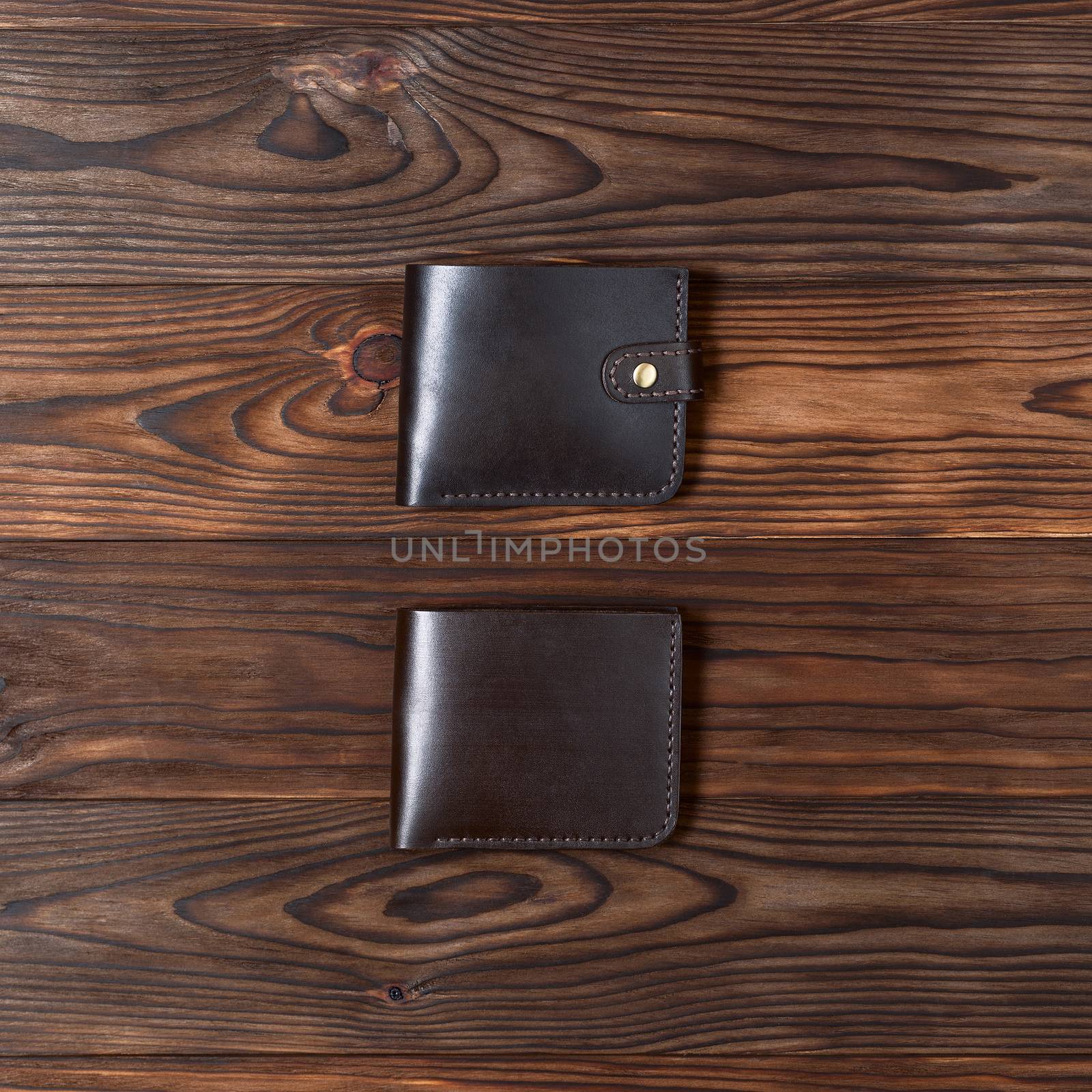Brown handmade leather gloss wallets on wooden textured background. Up to down view. Businessman wallet stock photo. by alexsdriver