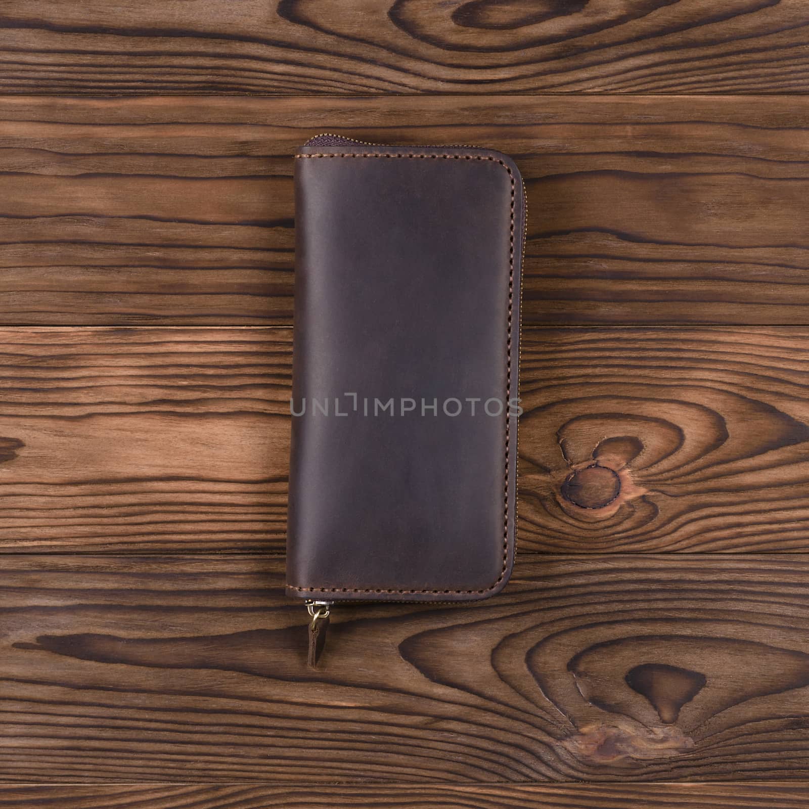 Brown color handmade leather porte-monnaie on wooden textured background.  Up to down view. Stock photo of luxury accessories.