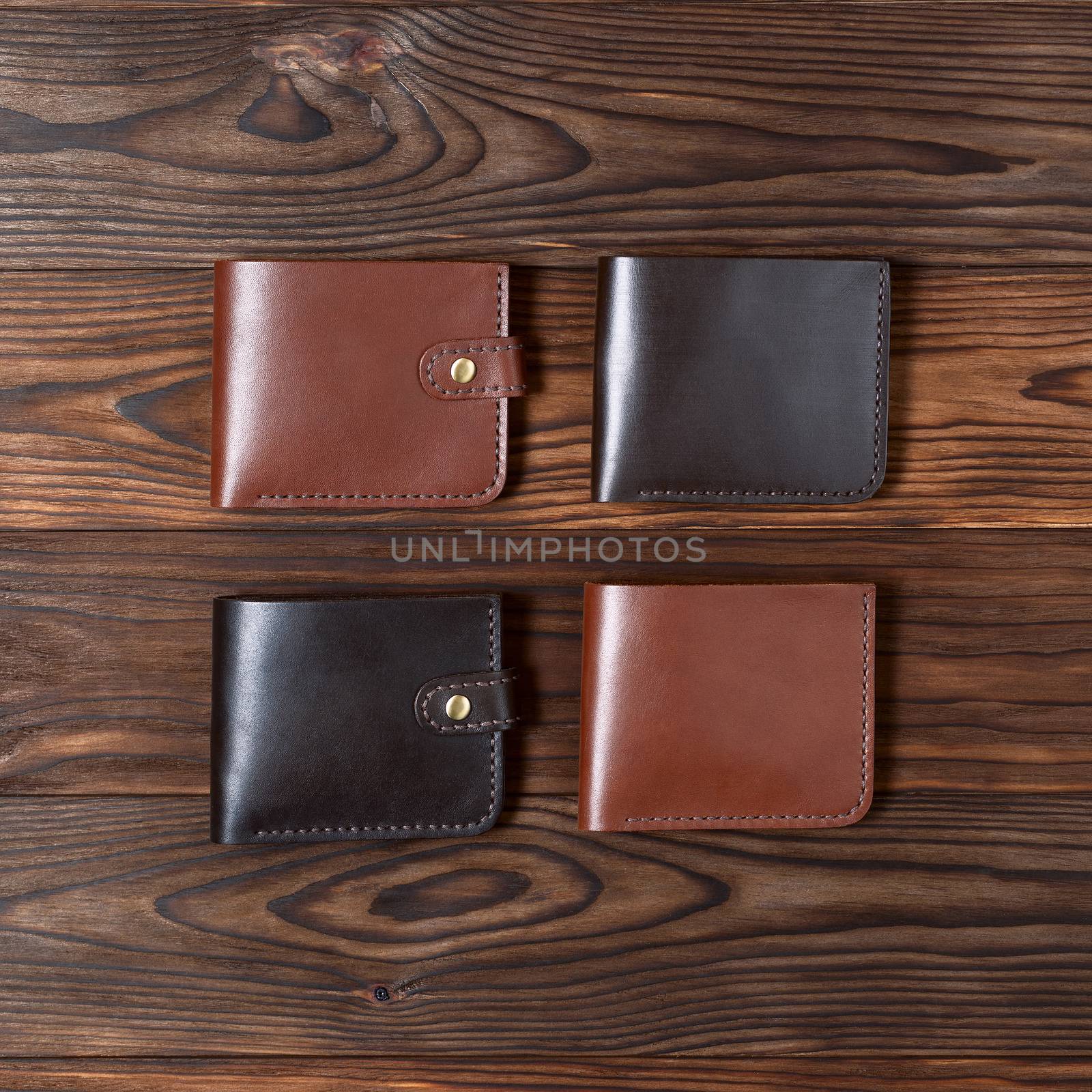 Four handmade leather gloss wallets on wooden textured background. Up to down view. Businessman wallet stock photo.