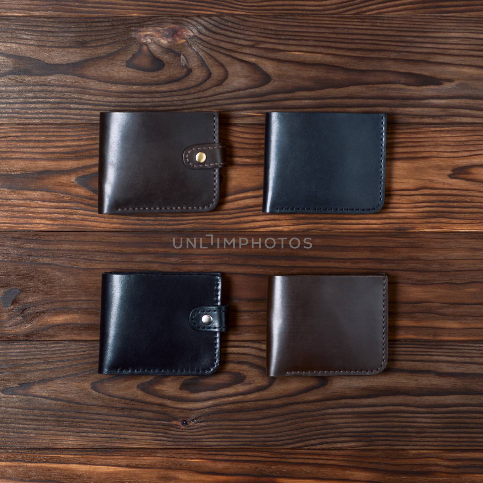 Four handmade leather gloss wallets on wooden textured background. Up to down view. Businessman wallet stock photo. by alexsdriver