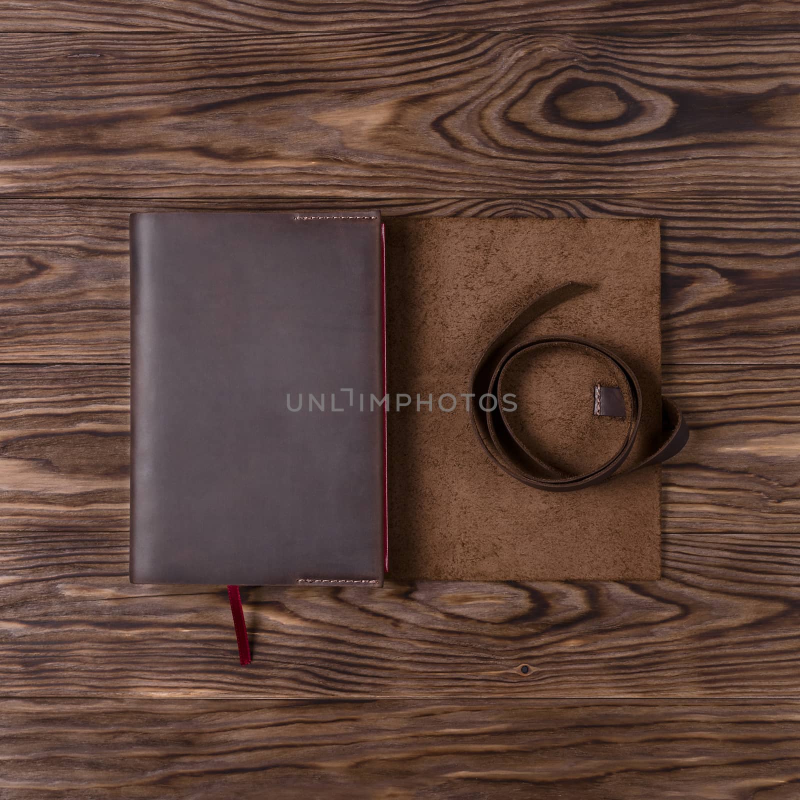 Brown handmade leather notebook cover with notebook on wooden background. Stock photo of luxury business accessories. Up to down view. by alexsdriver
