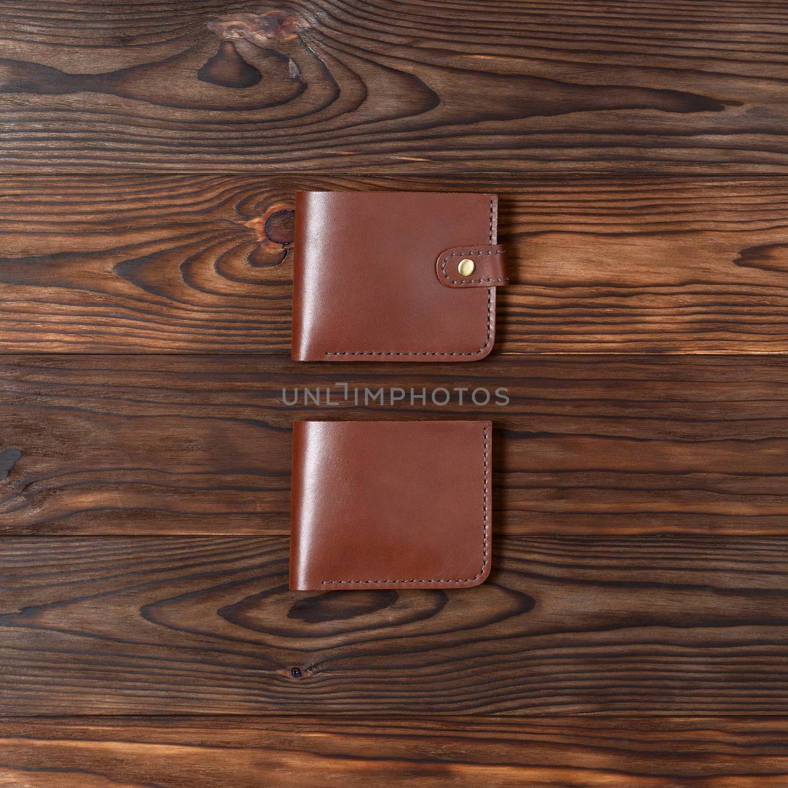 Red color handmade leather gloss wallets on wooden textured background. Up to down view. Wallet stock photo. by alexsdriver