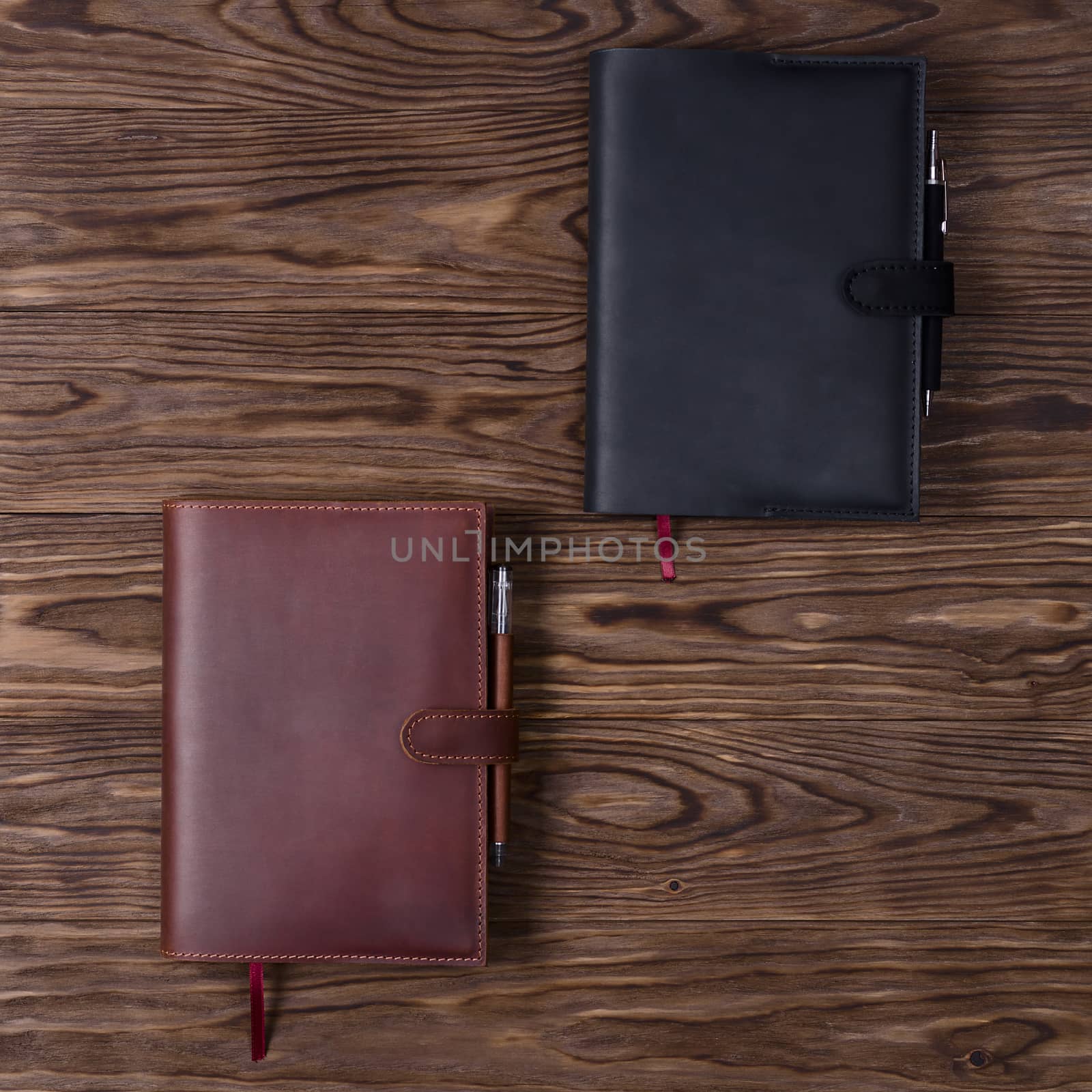 Black and brown handmade leather notebook cover with notebooks and pen on wooden background. Stock photo of luxury business accessories. Up to down view. by alexsdriver