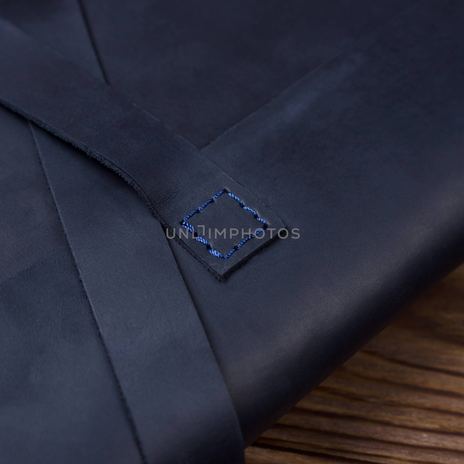 Blue handmade travel wallet lies on textured wooden backgroud closeup. Side view. Stock photo of businessman accessories.