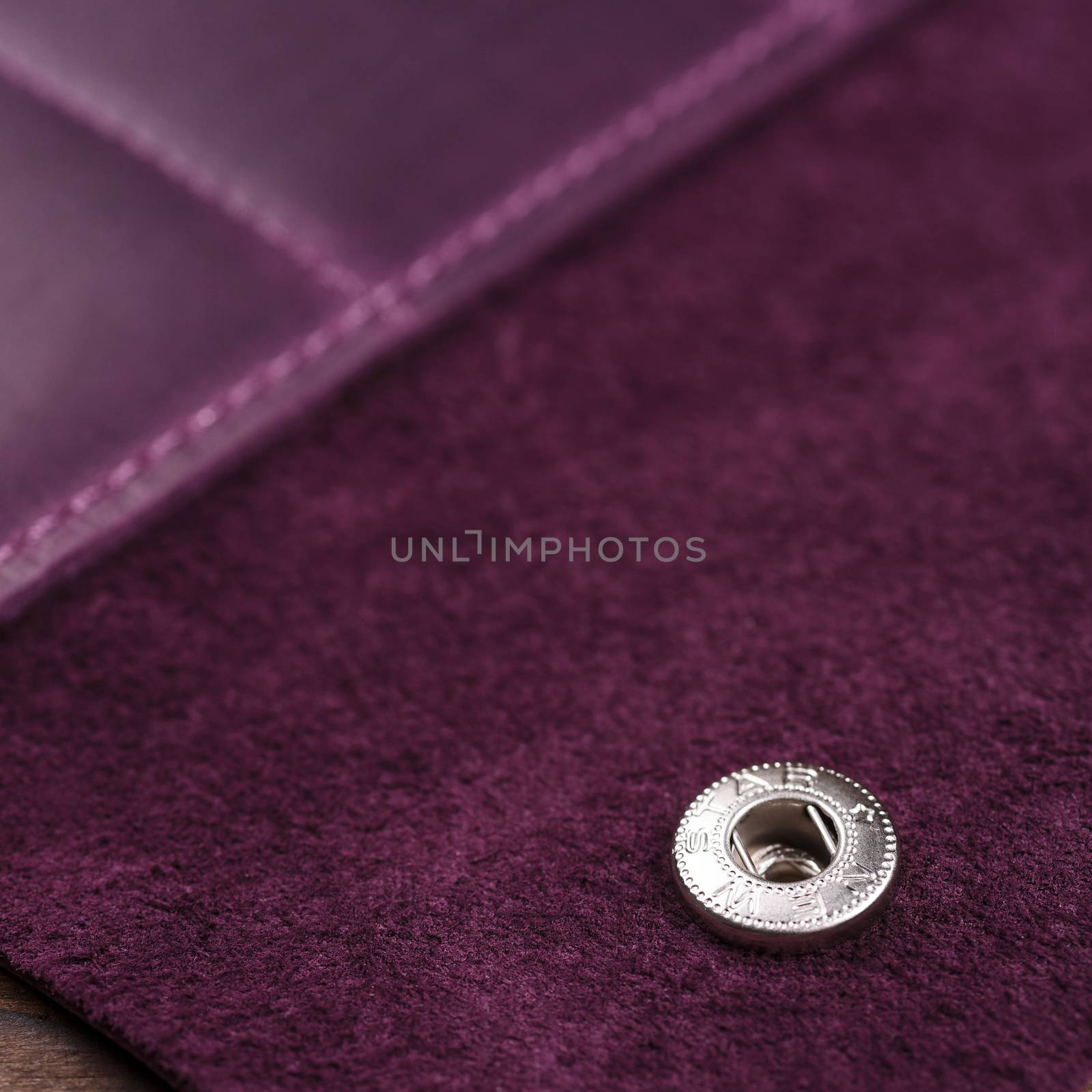 Part of purple handmade travel wallet lies on textured wooden backgroud closeup. Wallet is open and empty. Side view. Stock photo of businessman accessories.