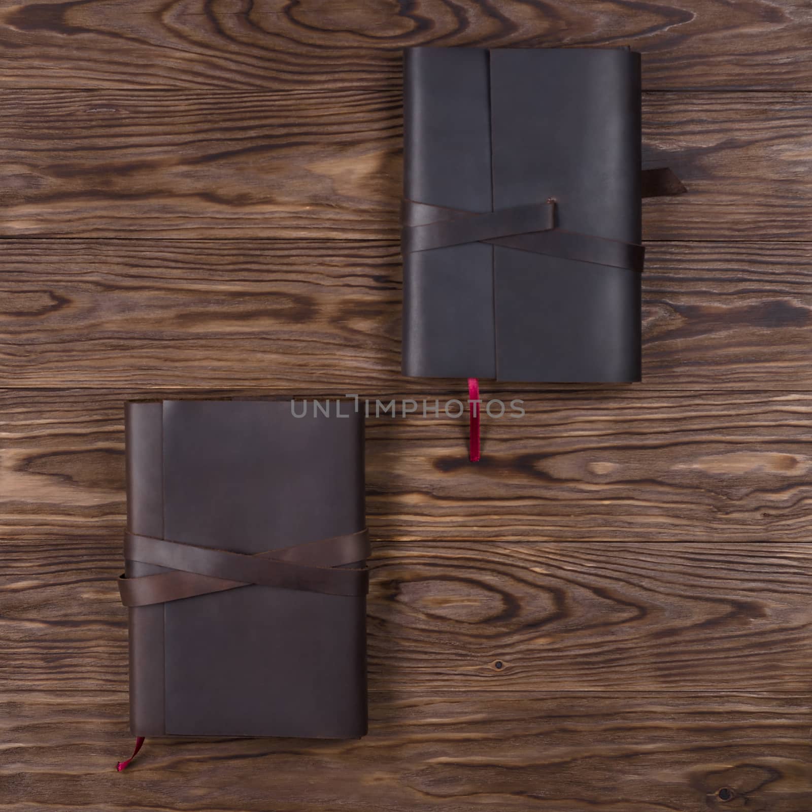 Black and brown handmade leather notebook cover with notebook on wooden background. Stock photo of luxury business accessories. Up to down view.