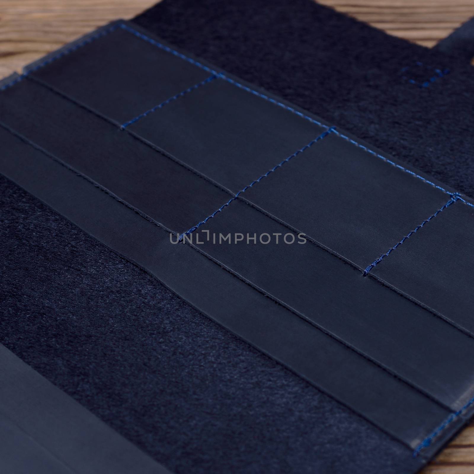 Blue handmade travel wallet lies on textured wooden backgroud closeup. Wallet is open and empty. Side view. Stock photo of businessman accessories.