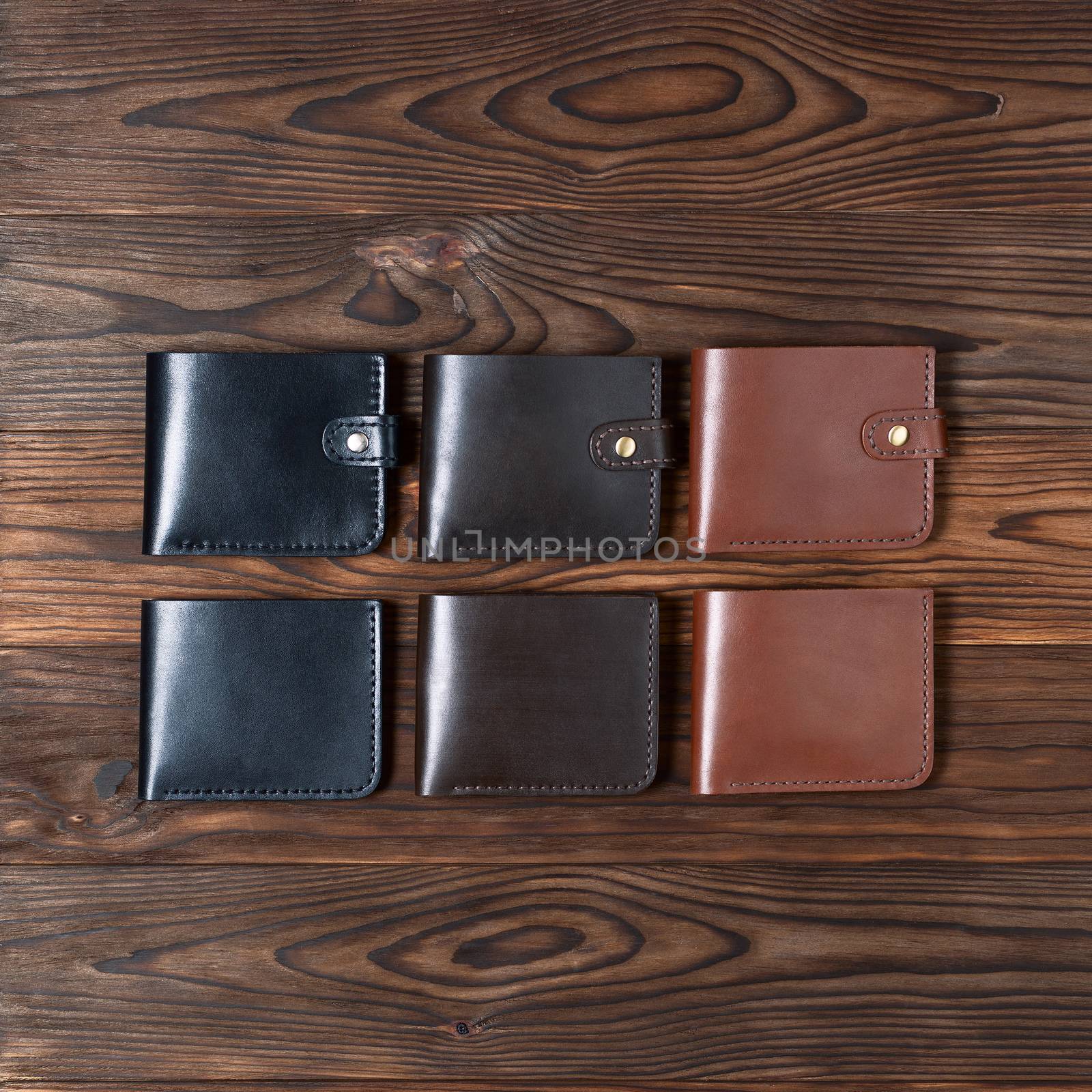 Six handmade leather wallets on wooden textured background. Up to down view. Wallet stock photo. by alexsdriver
