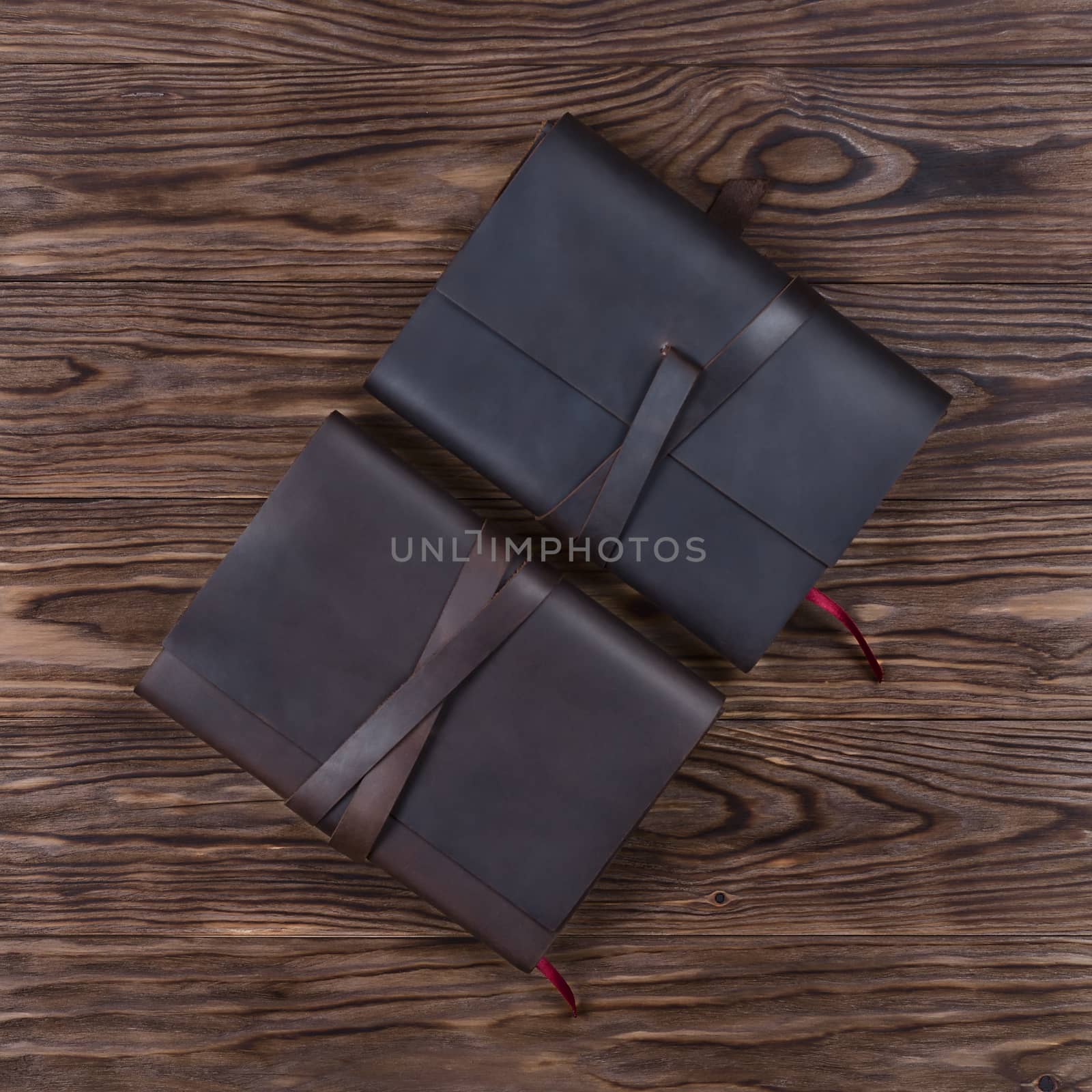Black and brown handmade leather notebook cover with notebooks on wooden background. Stock photo of luxury business accessories. Up to down view. by alexsdriver
