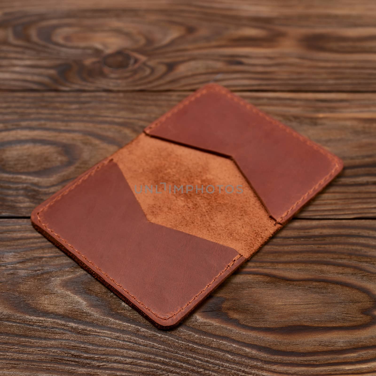 Handmade ginger leather cardholder on wooden background. Stock photo with blurred background. by alexsdriver