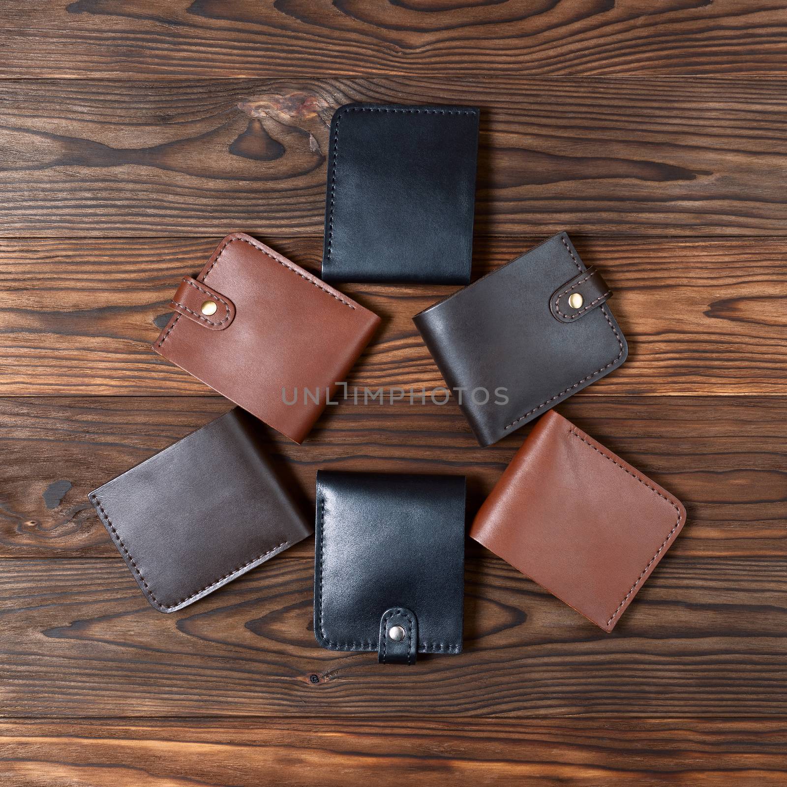 Six handmade leather wallets in the shape of a triangle on wooden textured background. Up to down view. Wallet stock photo.