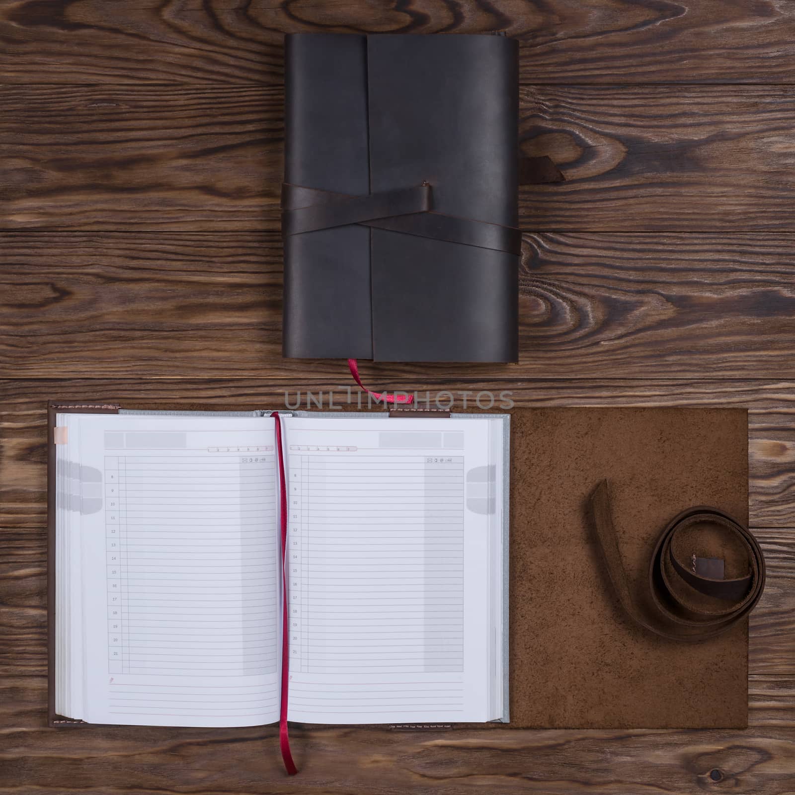 Black and brown opened handmade leather notebook cover with notebook inside on wooden background. Stock photo of luxury business accessories.