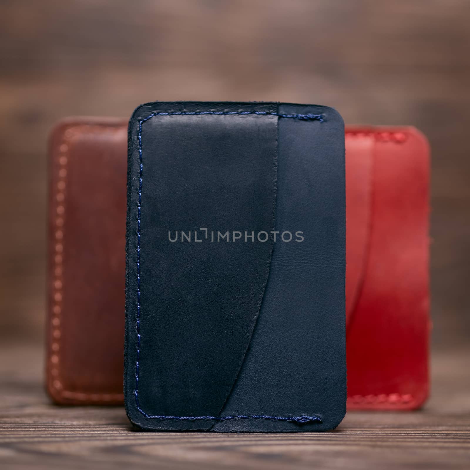 One pocket blue leather handmade cardholder. On blurred background stay other colour cardholders. Stock photo on blurred background.