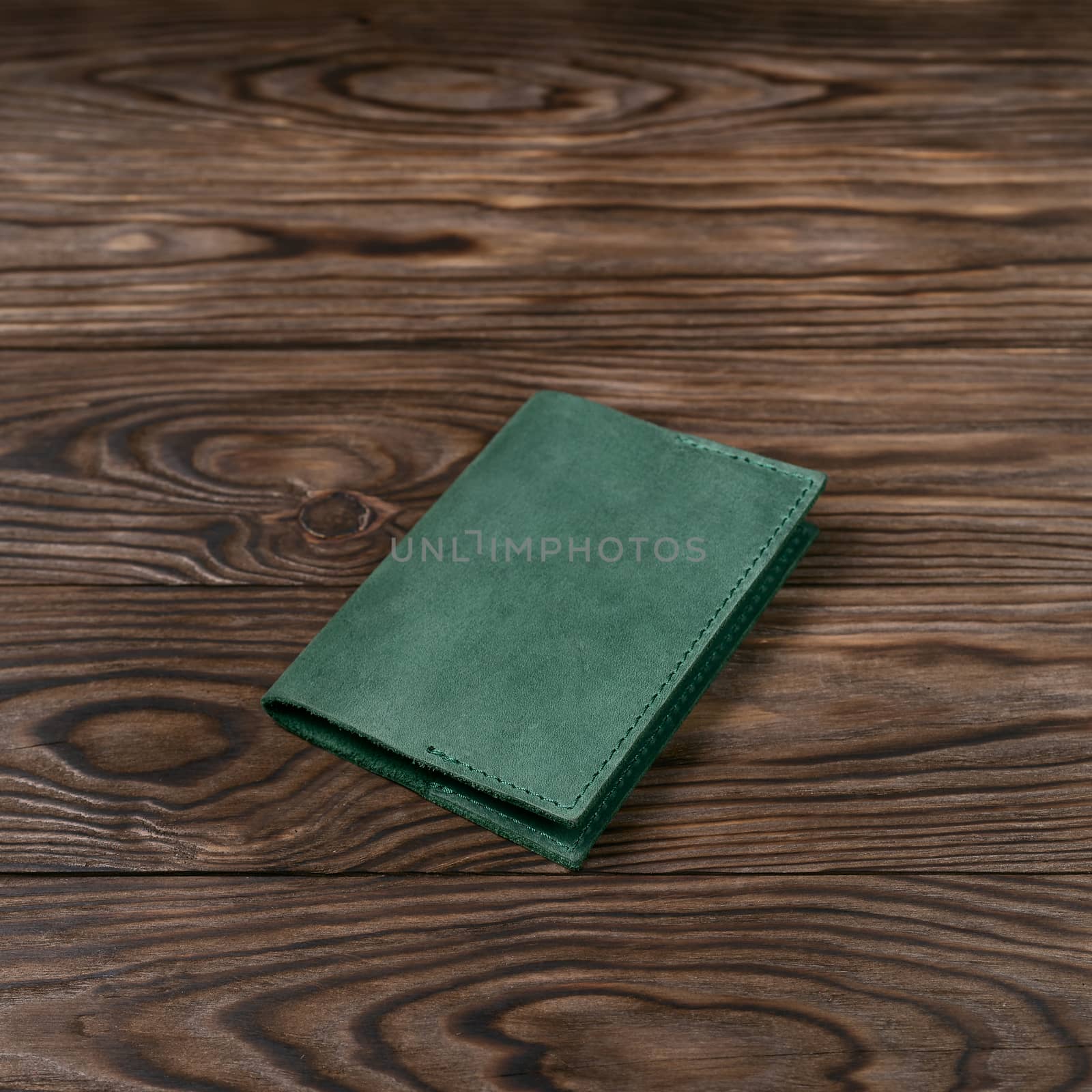 Mattle green color handmade leather passport cover on wooden textured background. Businessman`s accessory. by alexsdriver