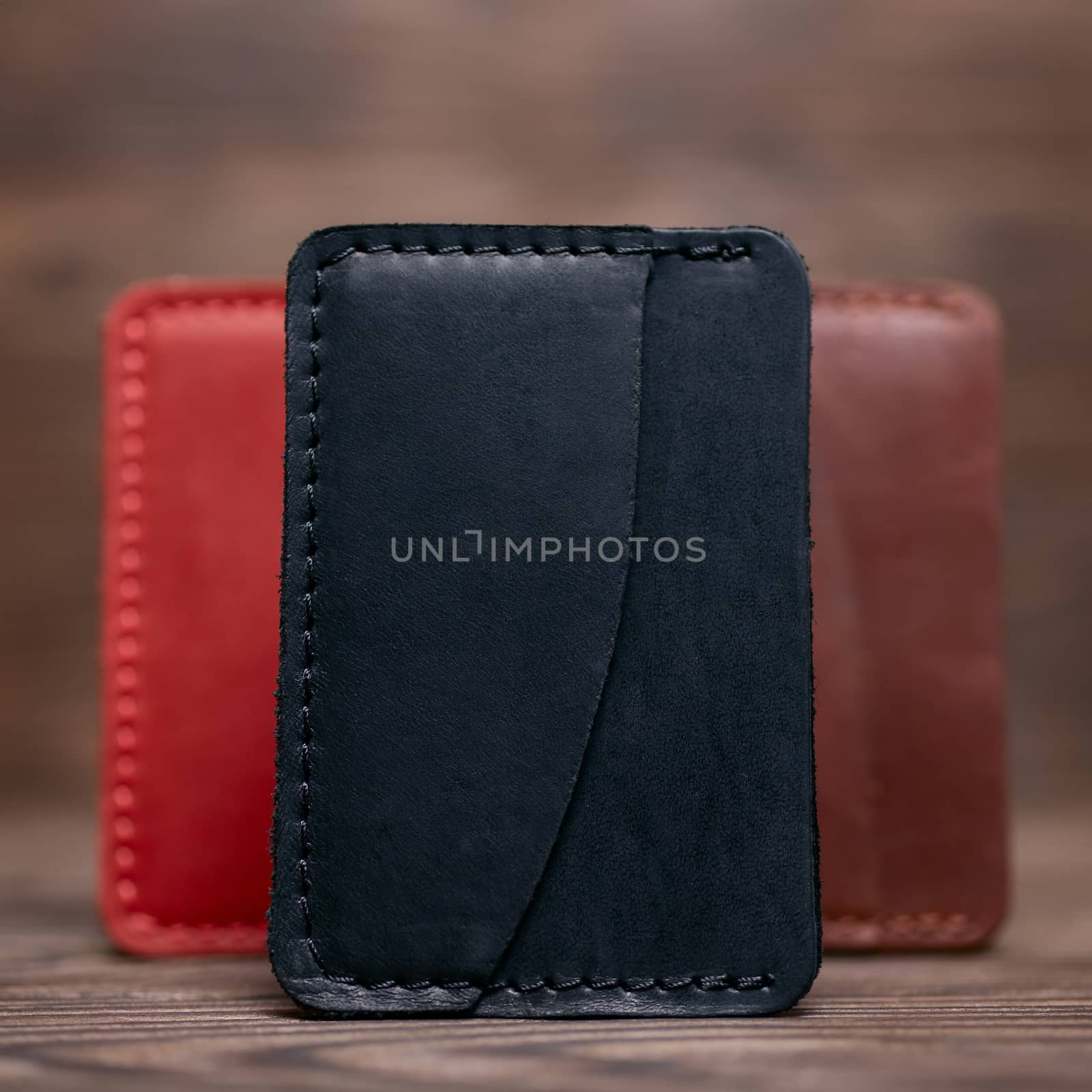 One pocket black leather handmade cardholder. On blurred background stay other colour cardholders. Stock photo on blurred background.